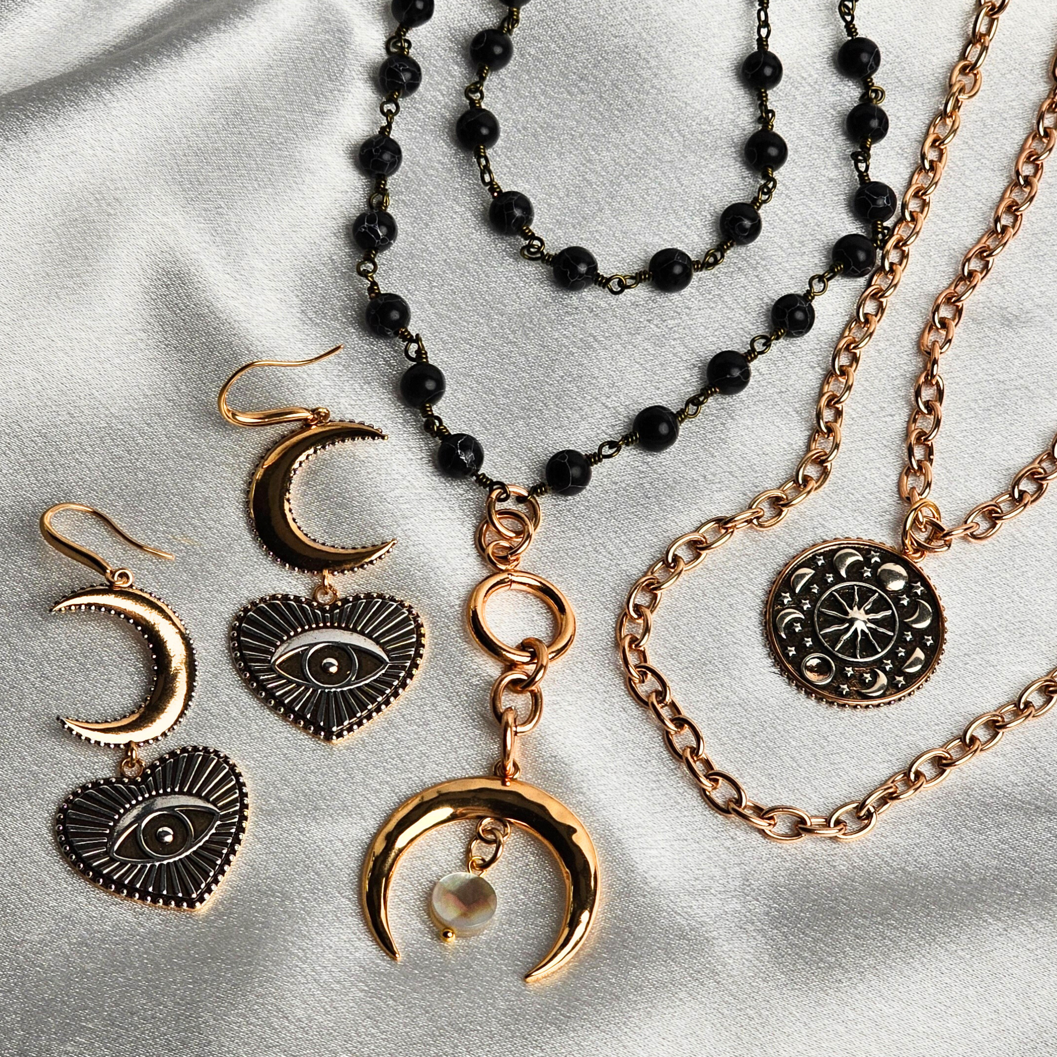 Gold and black jewelry set including necklaces, bracelets, and earrings on a light gray background