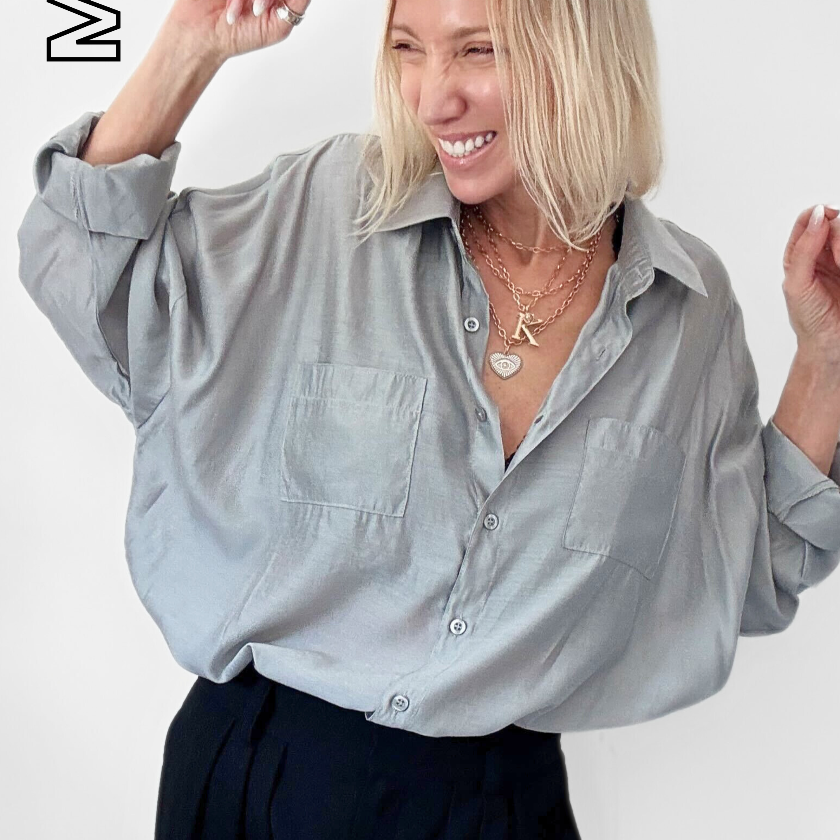 Woman wearing a light gray shirt and dark pants on a white background with 'MIST' branding.
