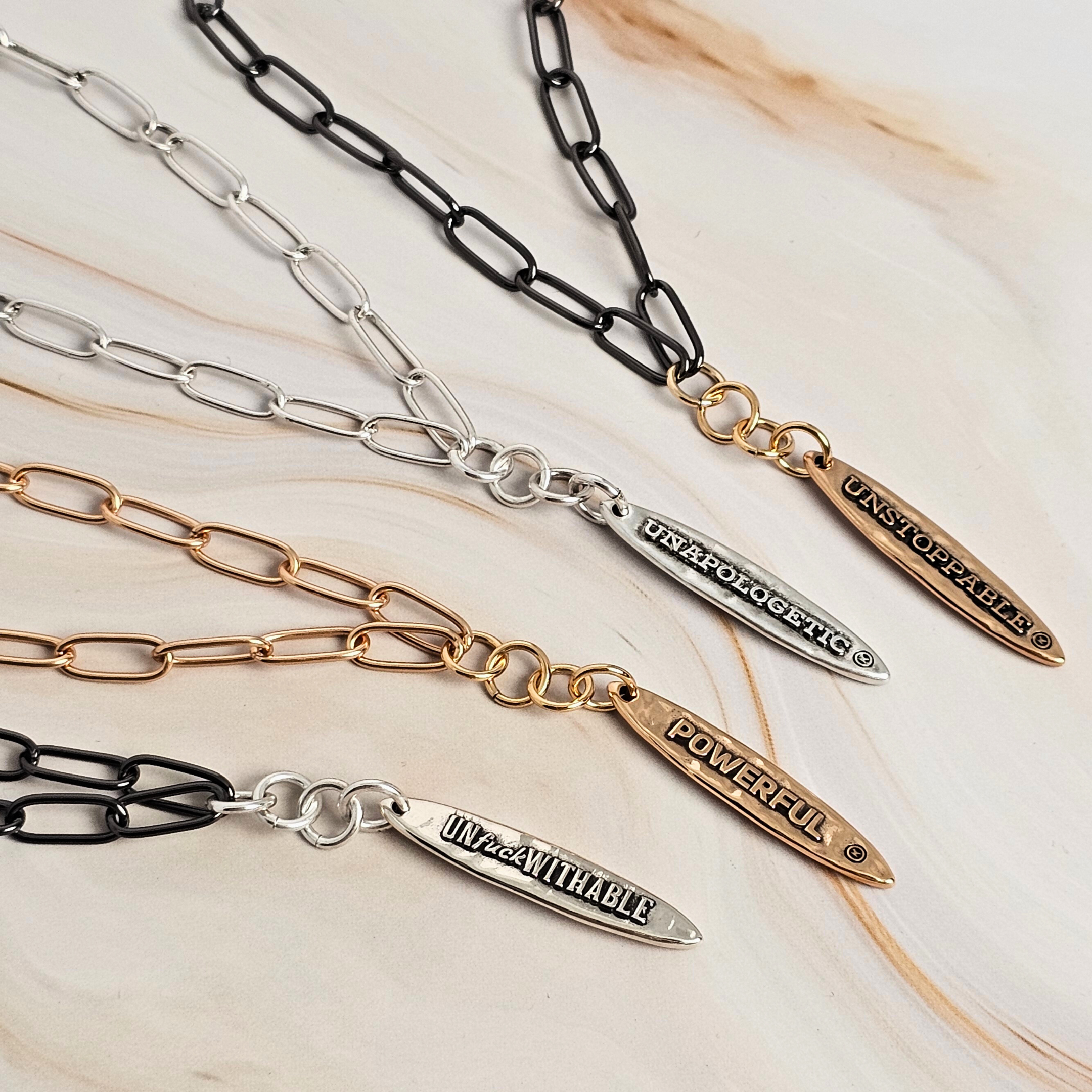 Set of chain necklaces with engraved pendants on a light background