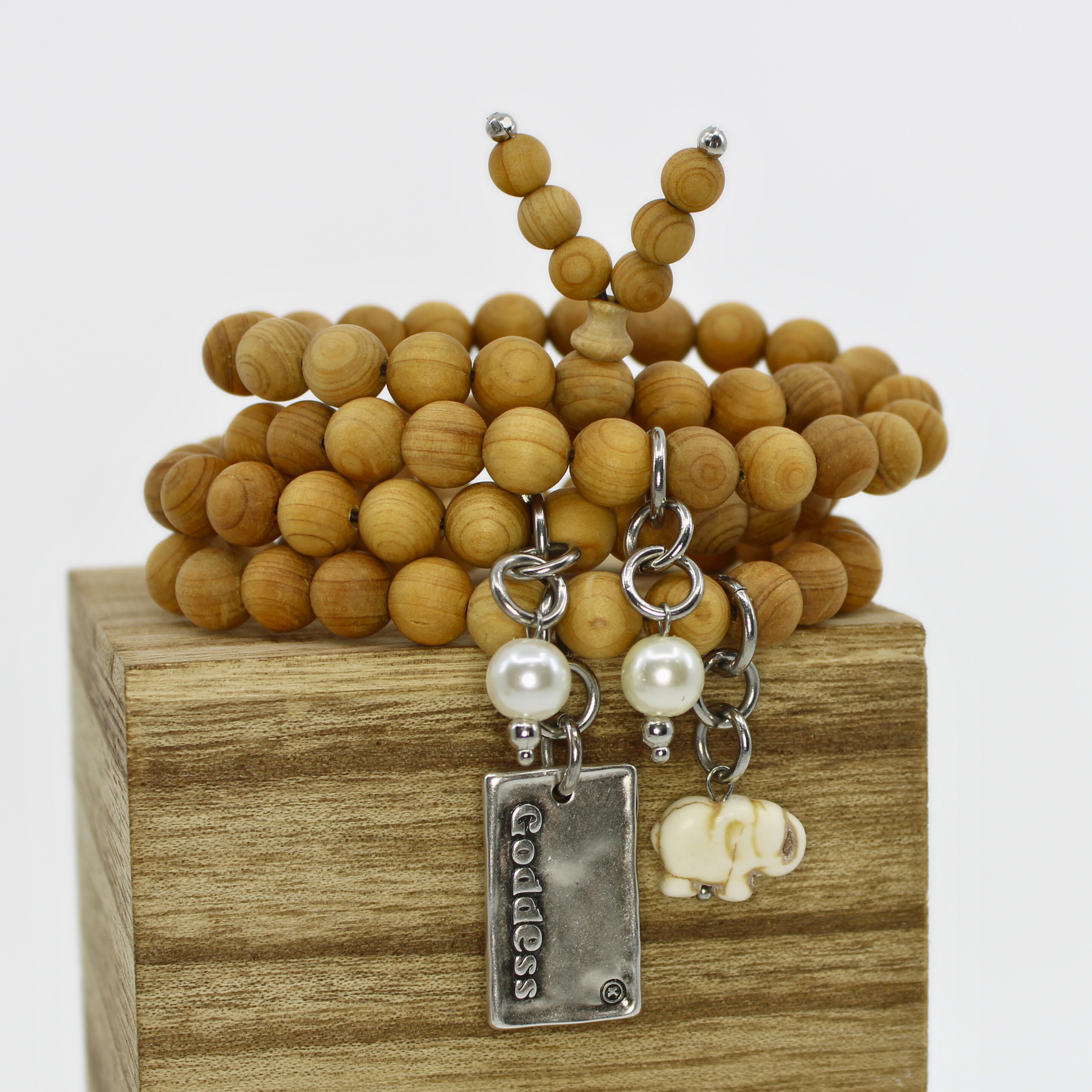 A wooden boho wrap bracelet with natural wood beads, white Howlite elephant accent, and pearl stones, displayed on a wooden box.