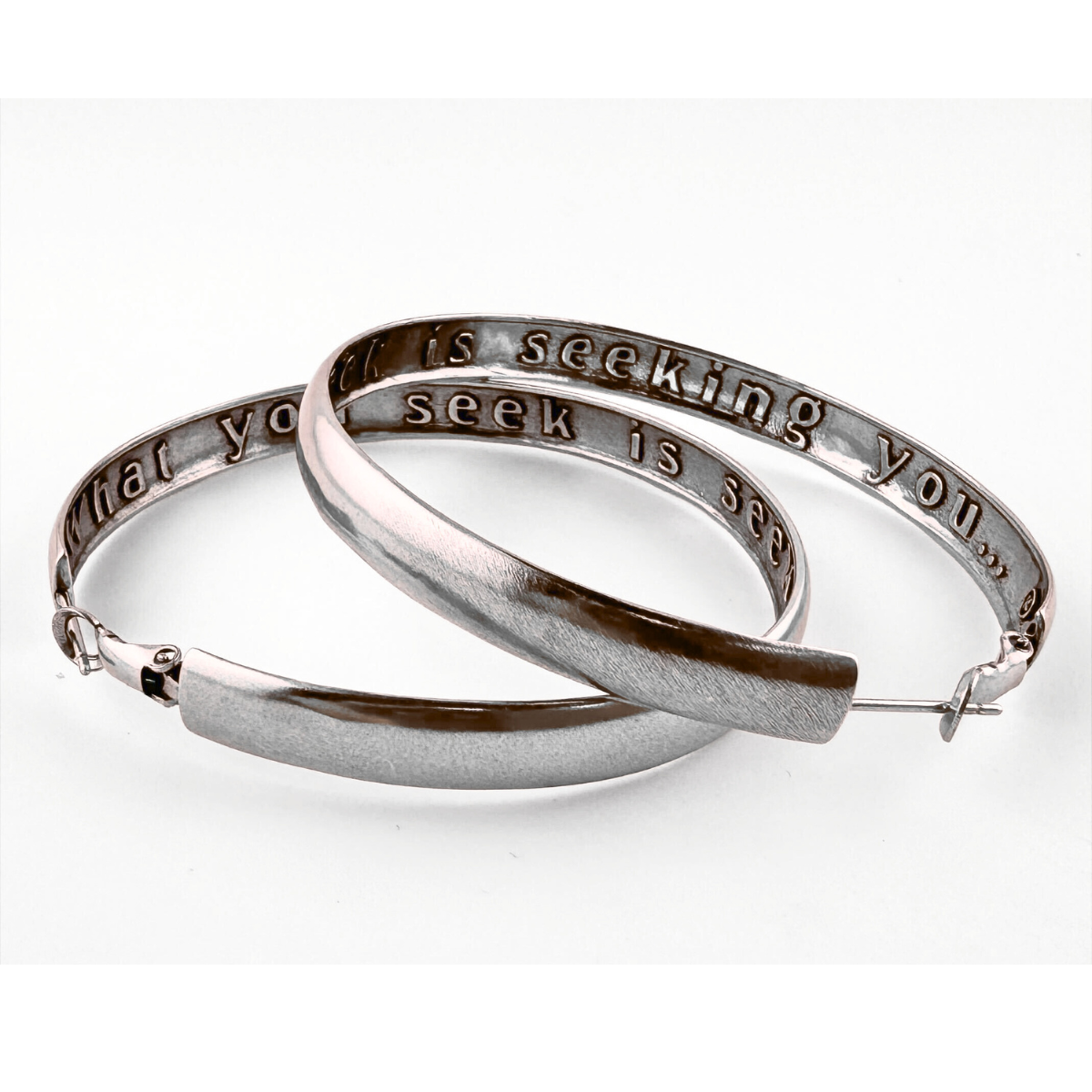 Silver hoop earrings with engraved text on a white background