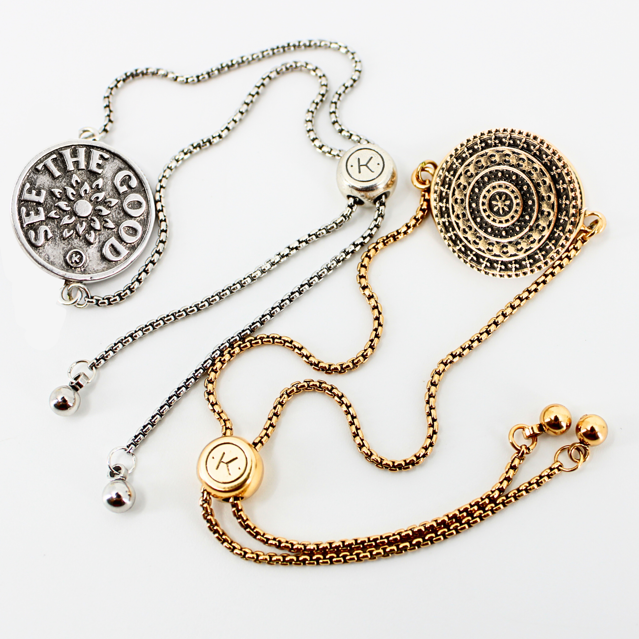 Two necklaces, one silver and one gold, with decorative pendants on a white background.