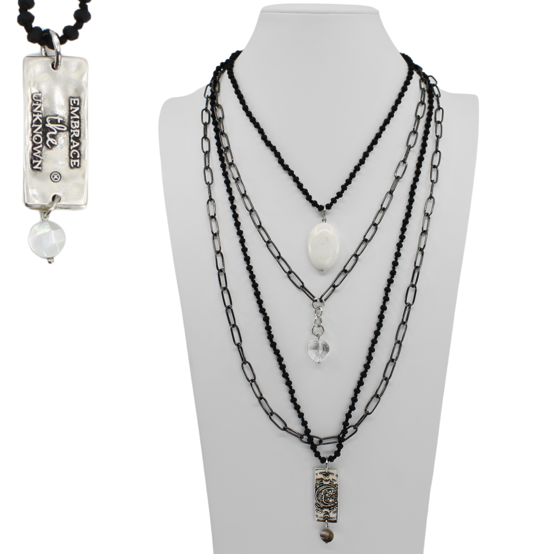Necklace with multiple chains and pendants on a mannequin bust, with a pendant labeled 'Embrace Unknown' on the left.