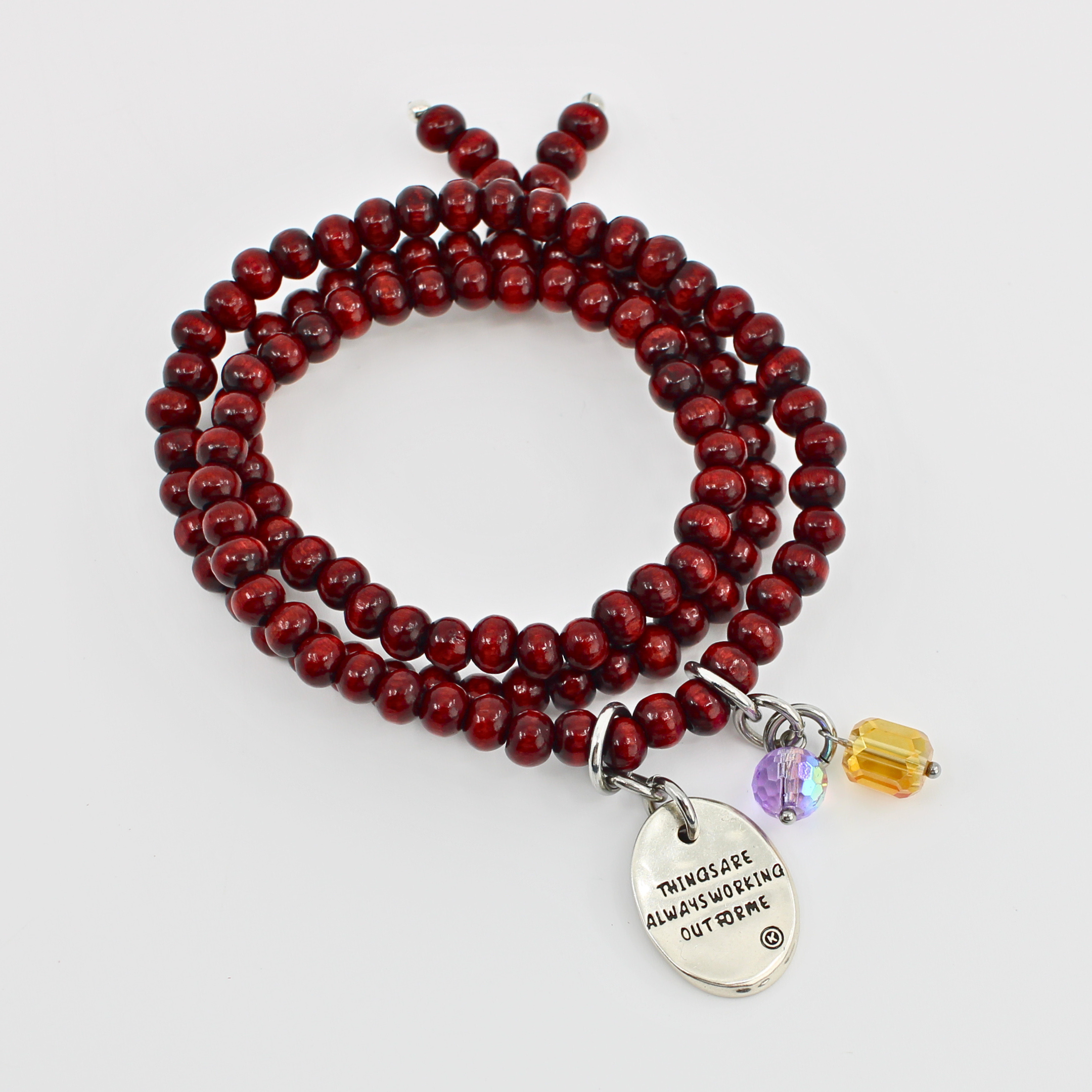 Red beaded bracelet with a silver charm and yellow accent bead on a white background