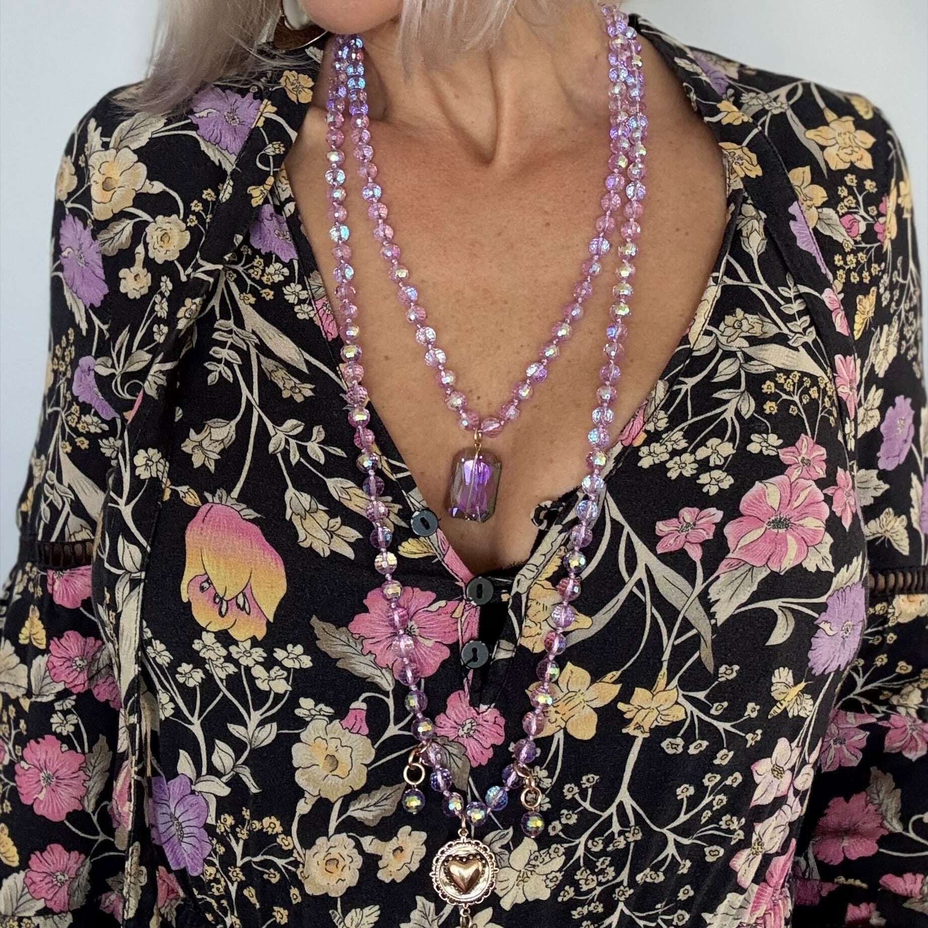Person wearing a floral dress with a long beaded necklace
