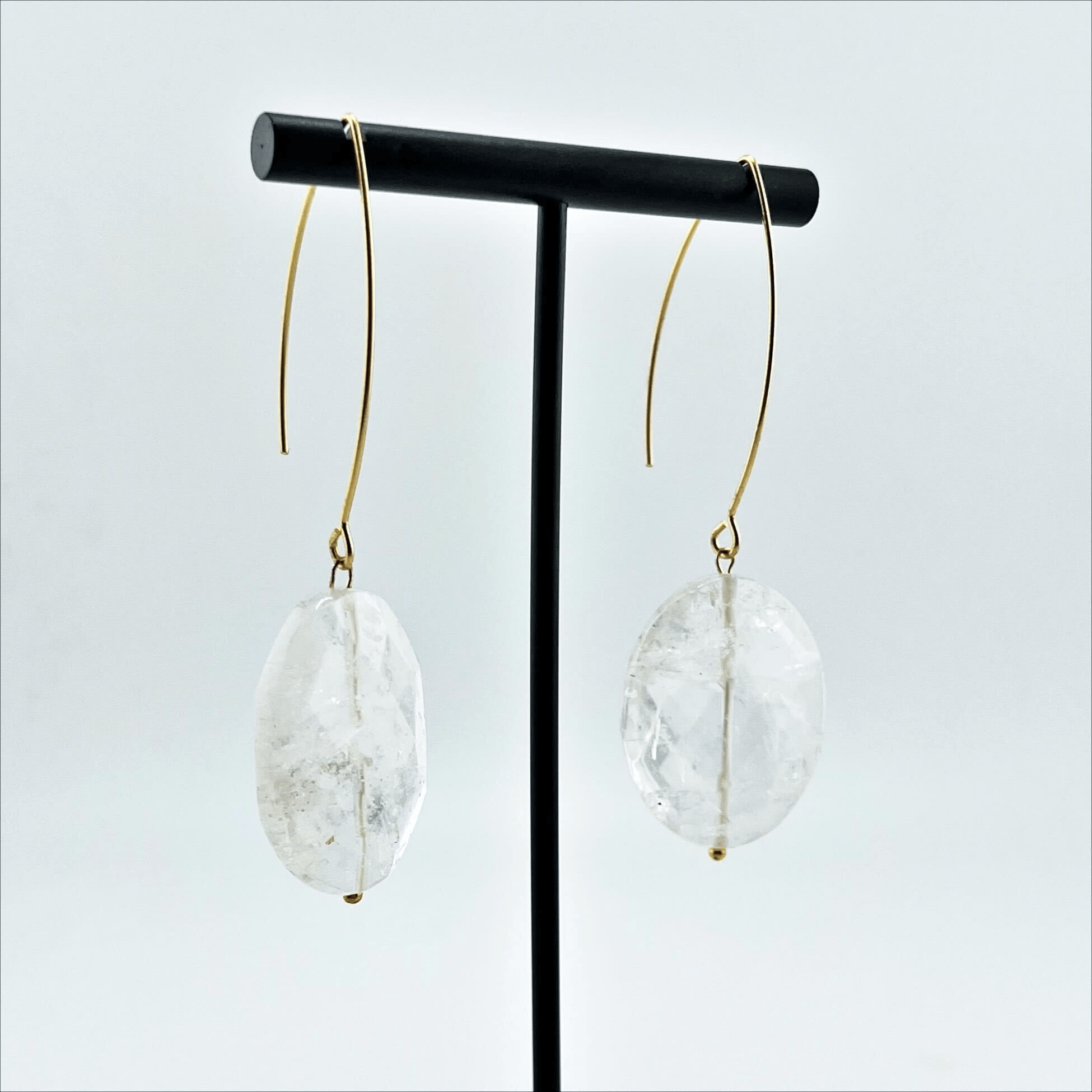 A person wearing large stone drop earrings with a V-shape wire earring holder.
