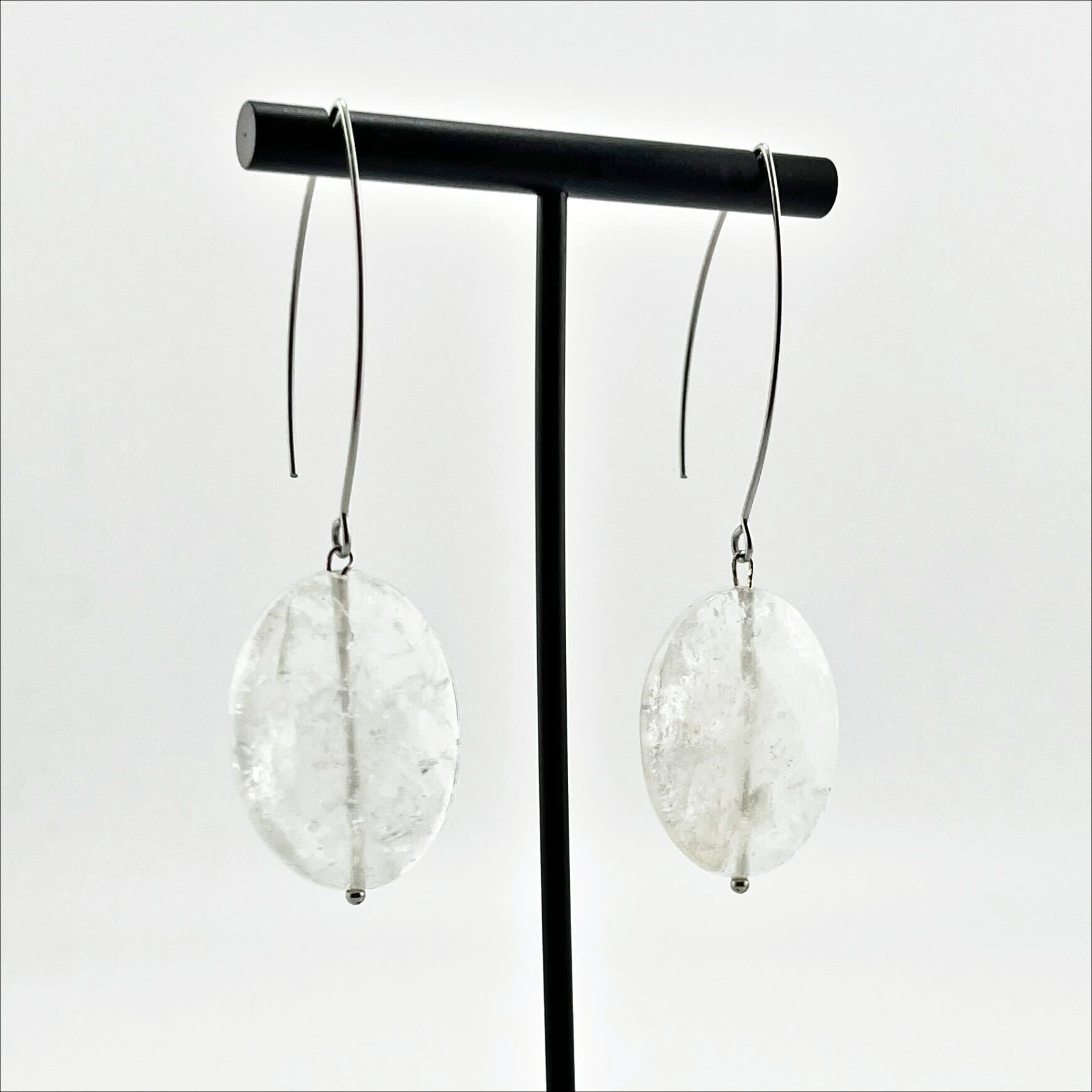 A person wearing large stone drop earrings with a V-shape wire earring holder.