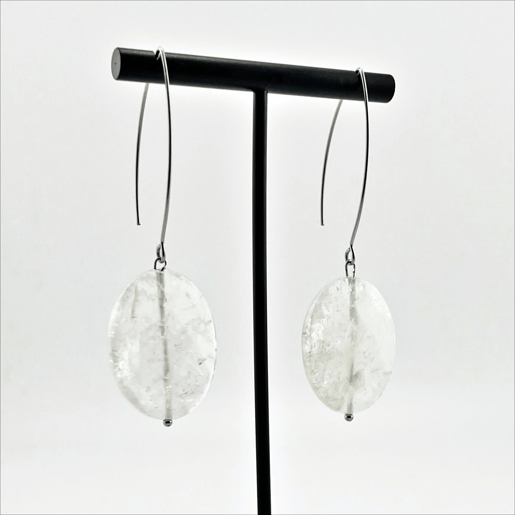 A person wearing large stone drop earrings with a V-shape wire earring holder.