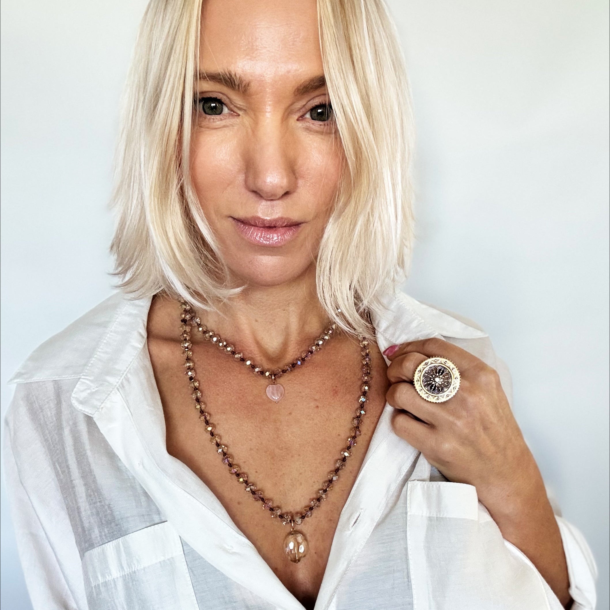 Person wearing a white shirt with jewelry on a plain background
