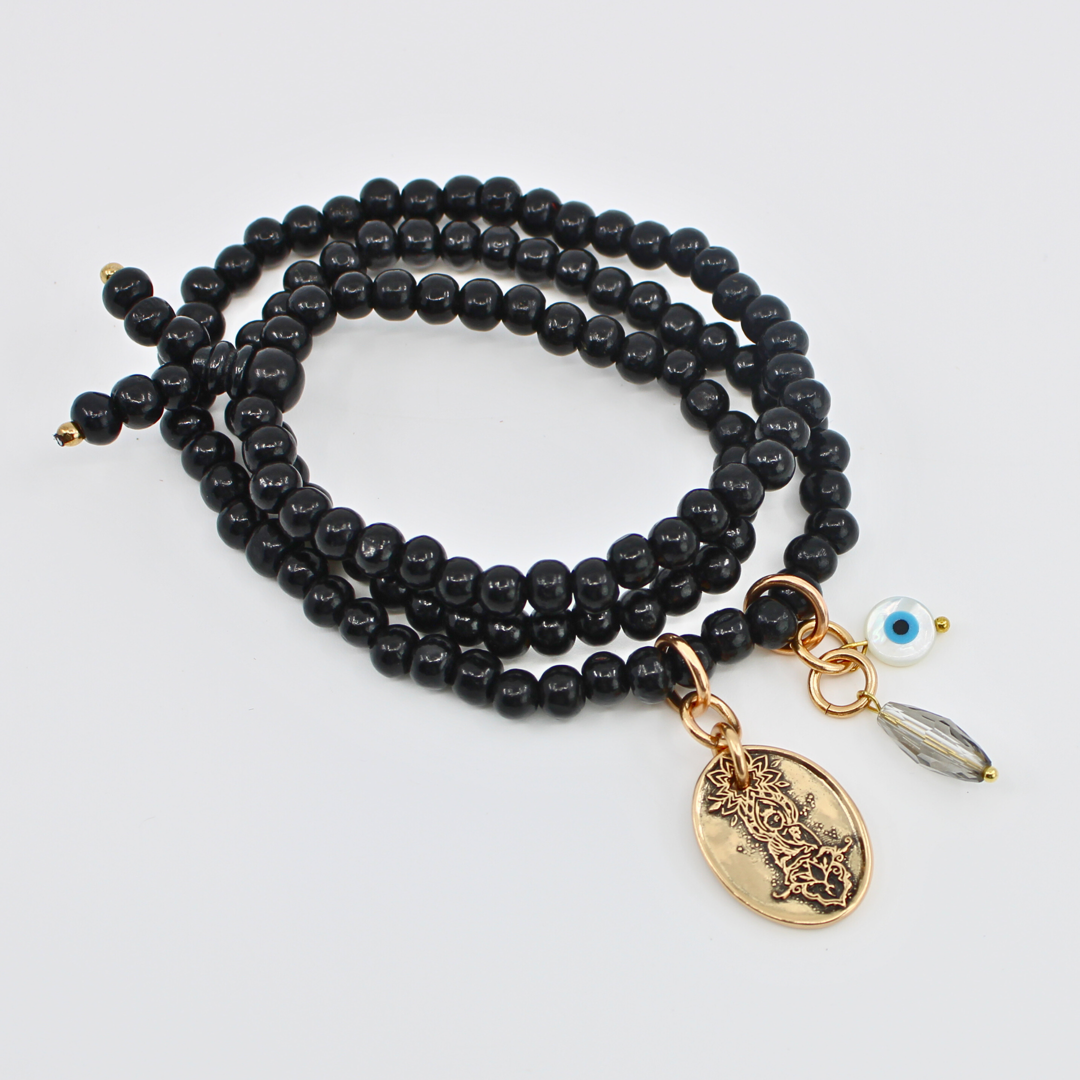 Black beaded necklace with gold and silver charms on a light gray background