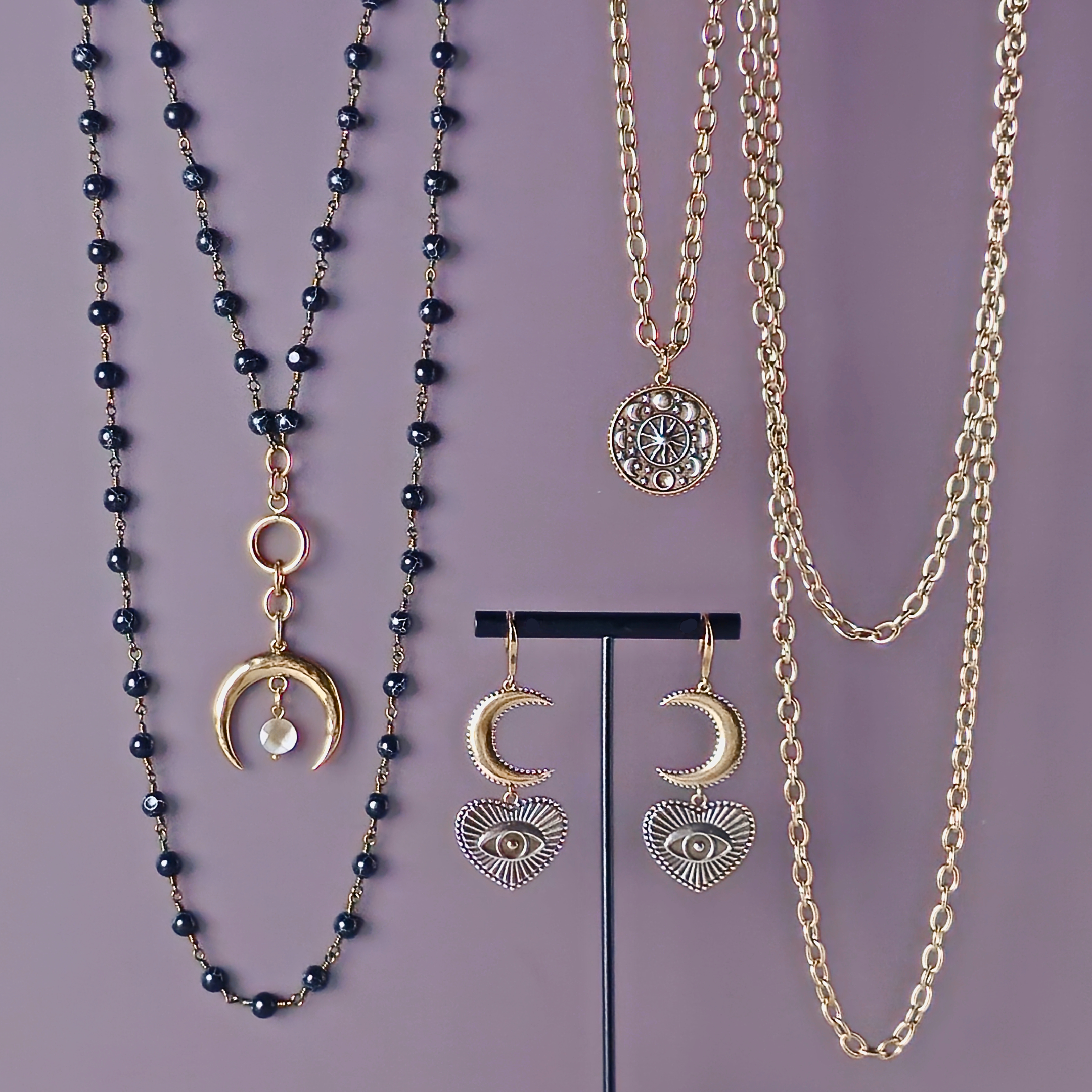 Jewelry set with black beaded necklace, gold chain, and earrings on a purple background