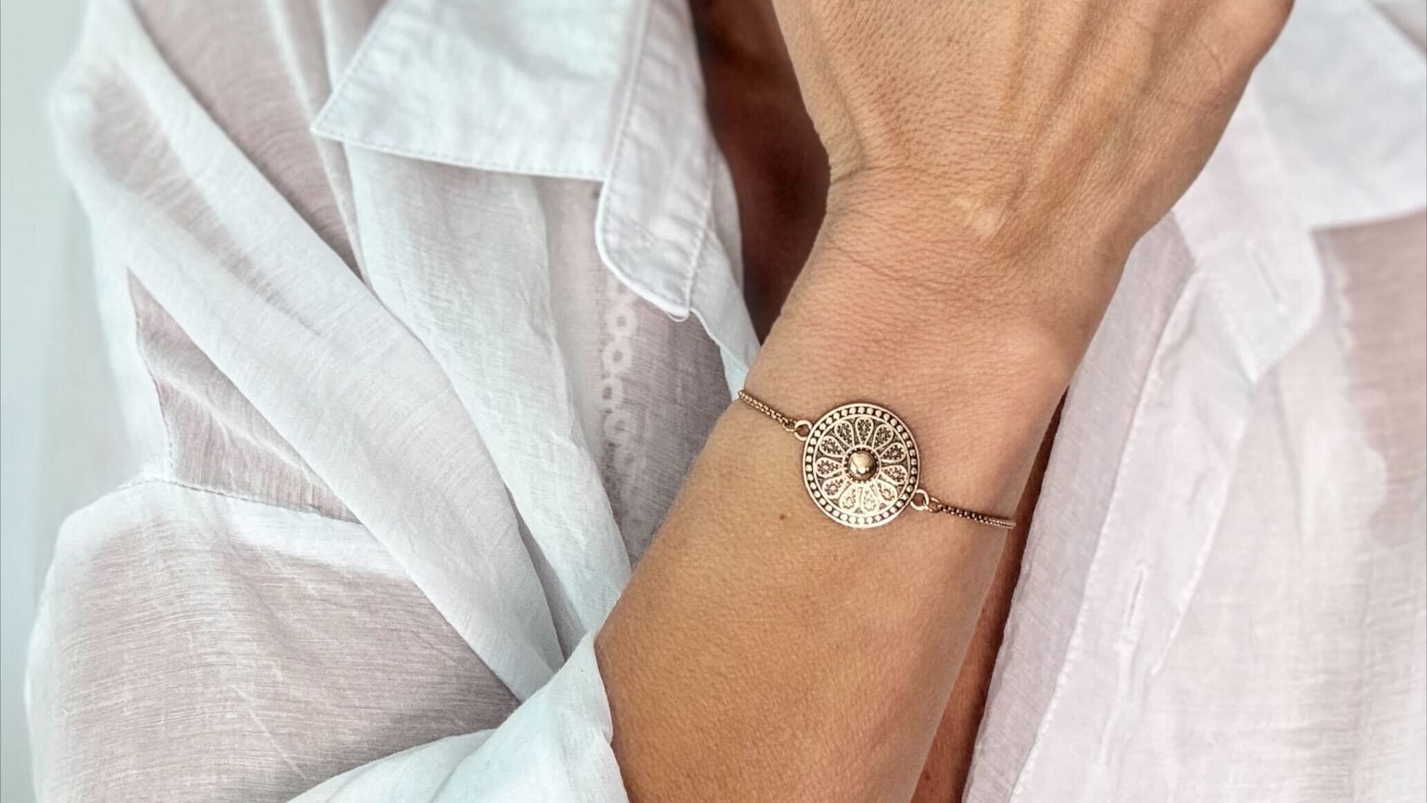 Woman wearing a gold bracelet and ring, with a blurred background
