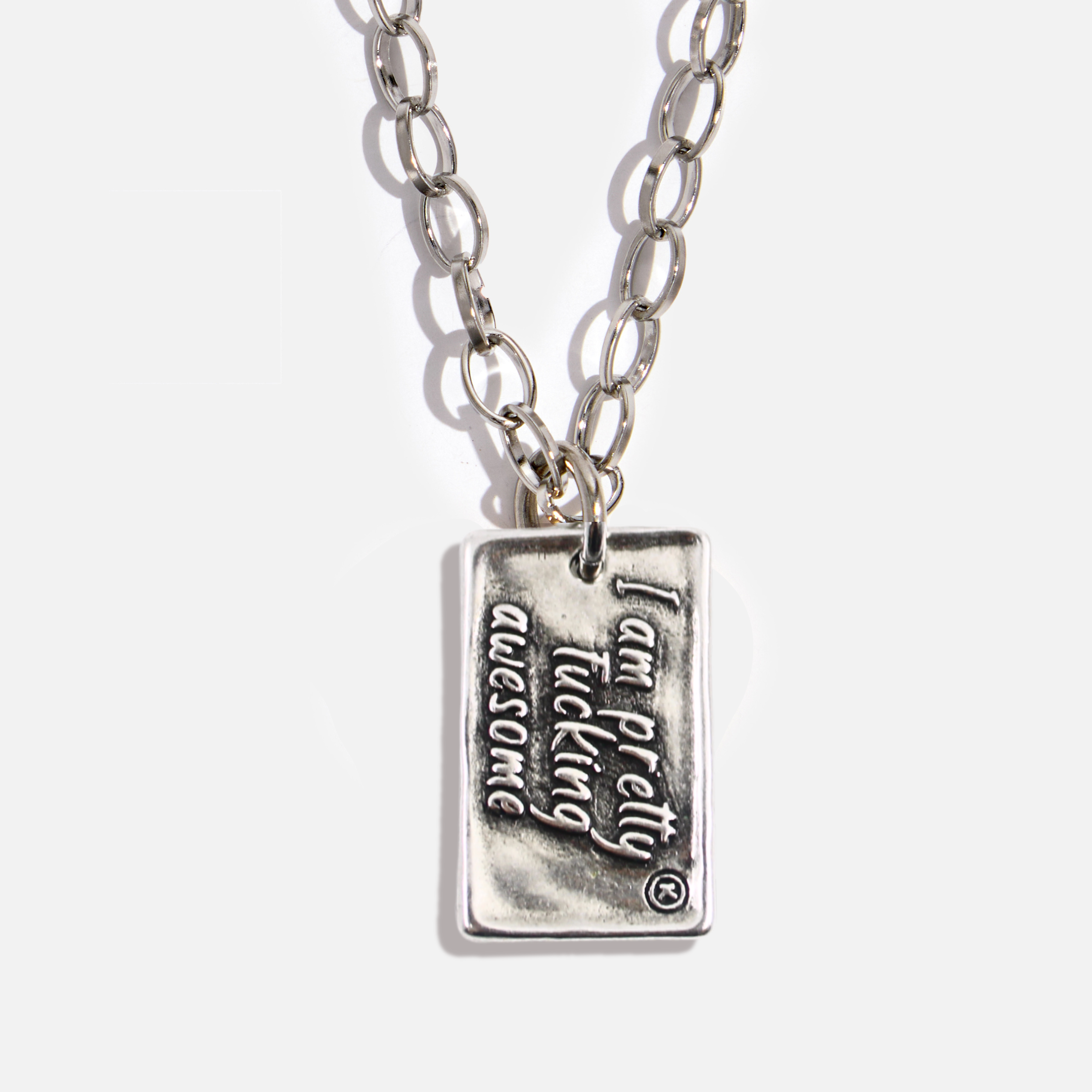Silver necklace with a pendant that reads 'I am pretty tucking awesome' on a white background