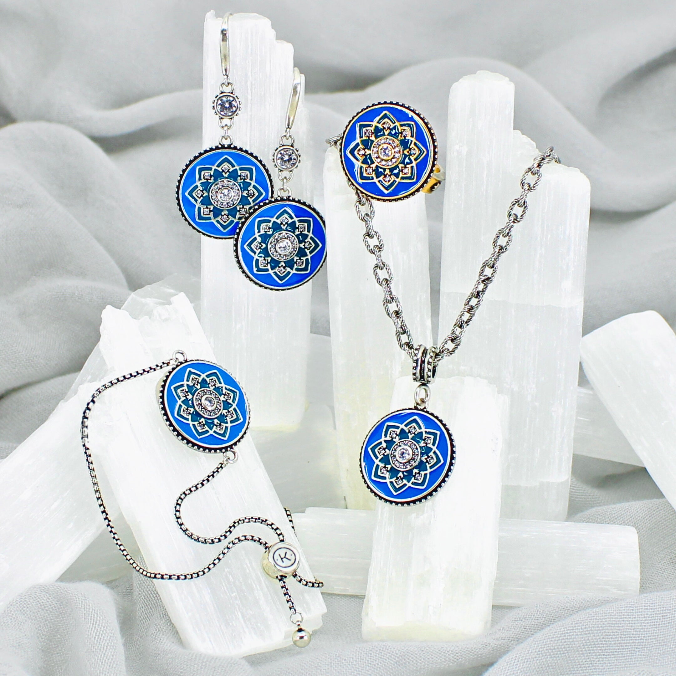 Jewelry set with blue and silver mandala designs on a white fabric background