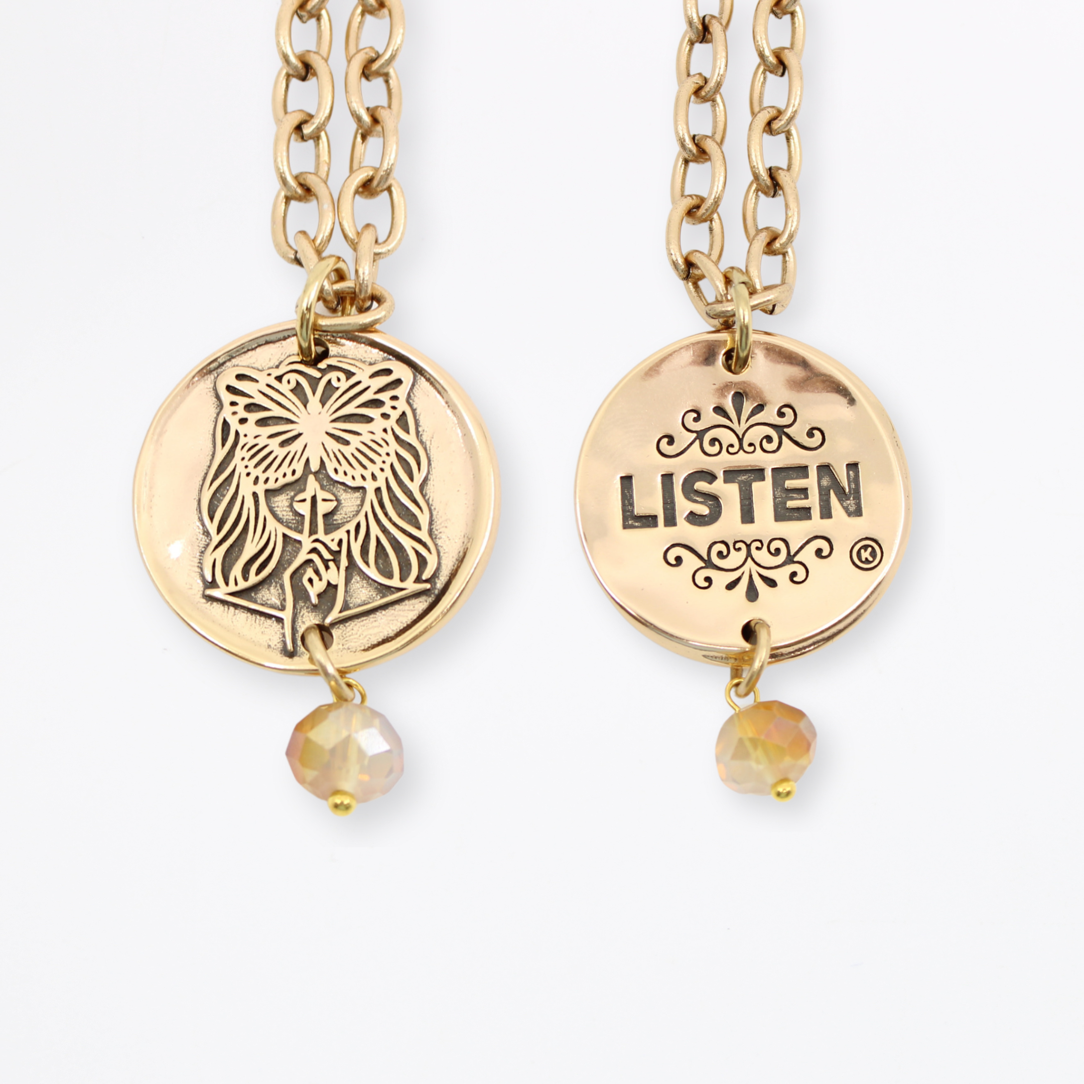 Two chain necklaces with round pendants: one gold with LISTEN adorned in plated brass and small beads, the other gold featuring a face design. Each piece exudes charm, enhanced by subtle crystal accents.