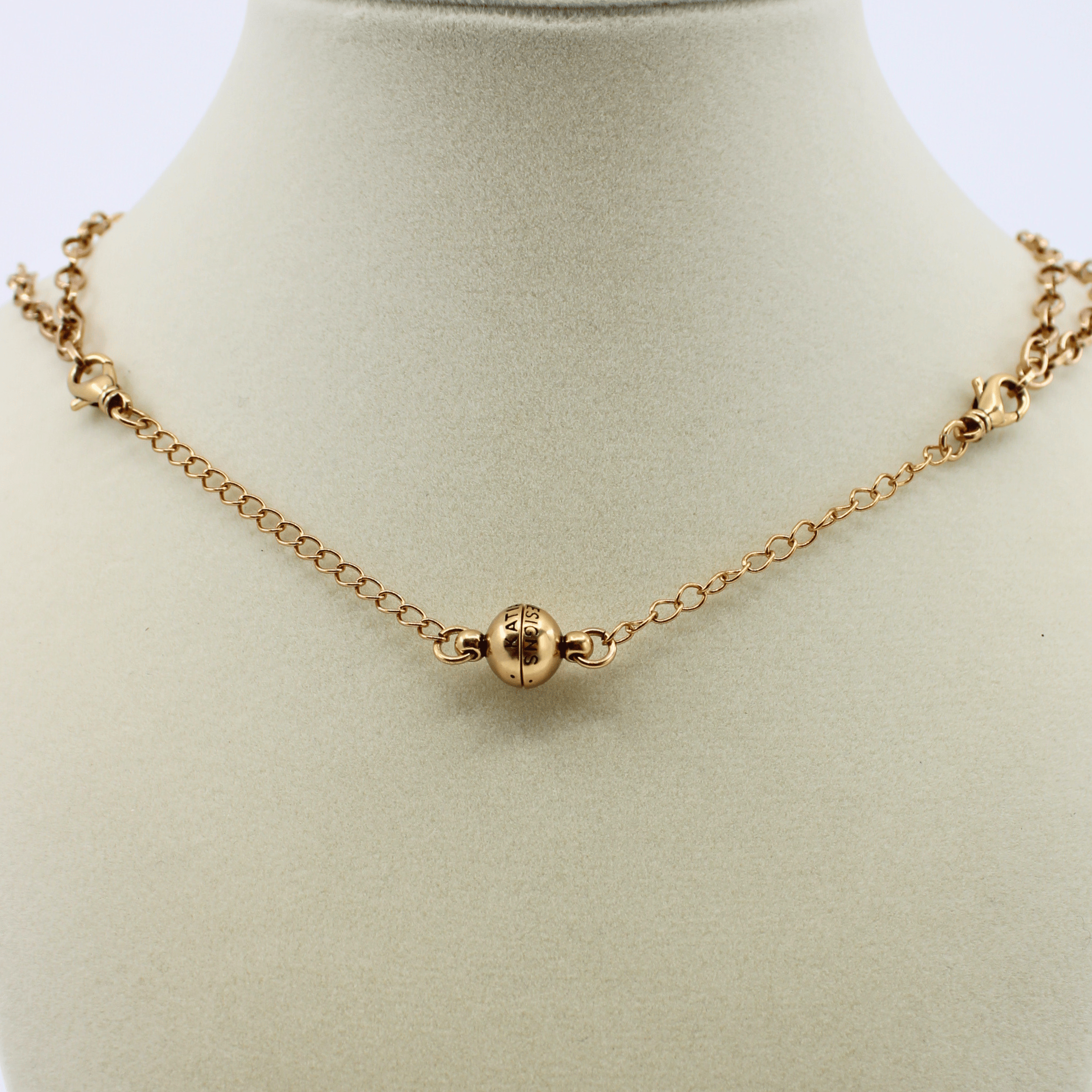 Gold necklace on a mannequin bust with a plain background