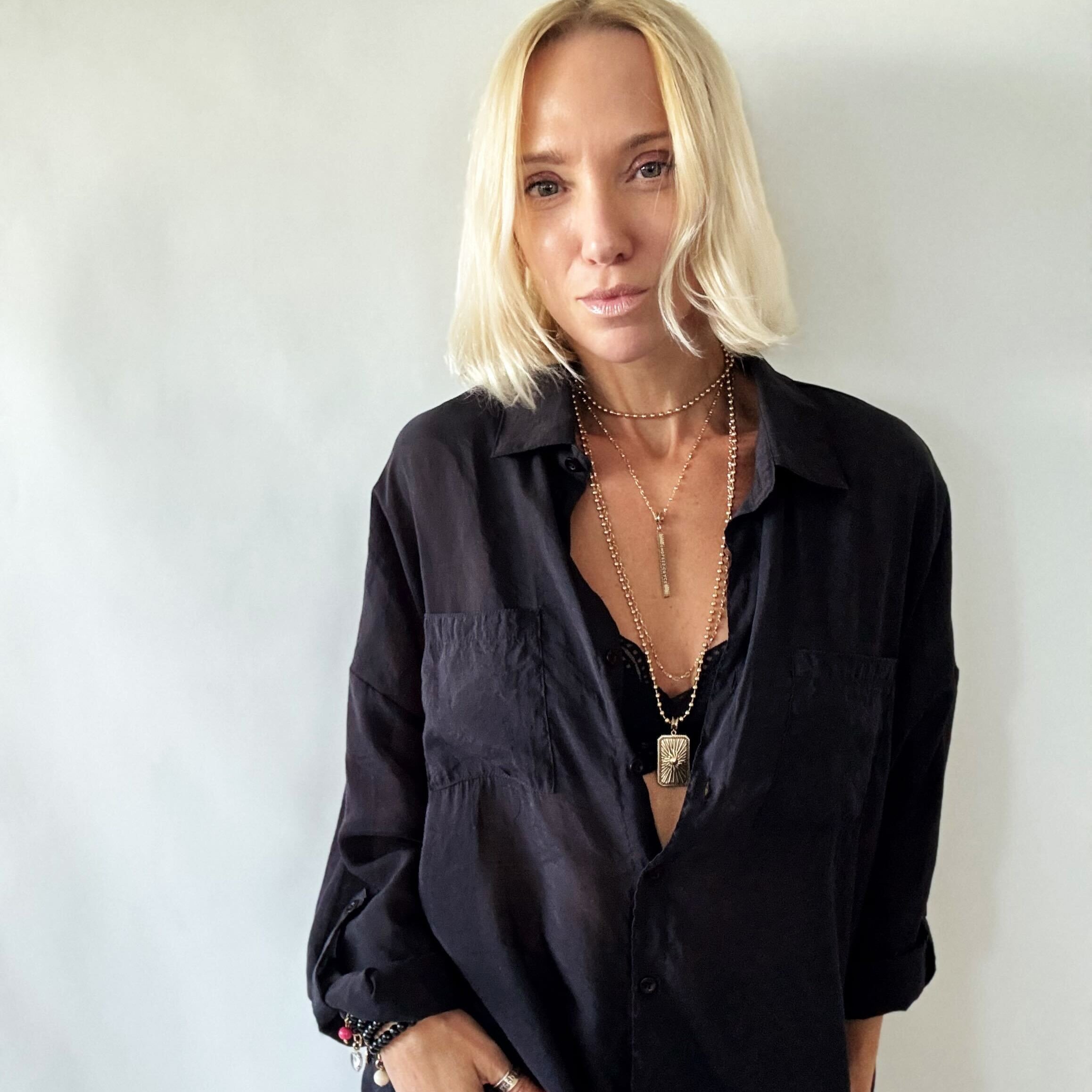 Woman wearing a black oversized shirt and ripped jeans against a white background
