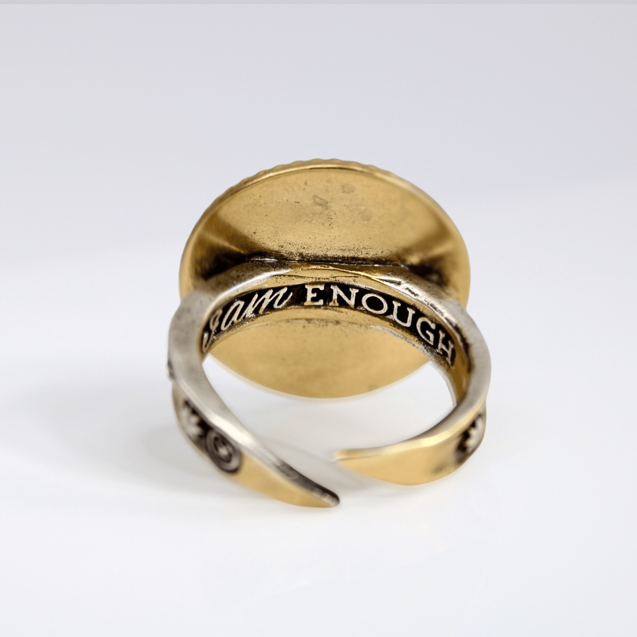 Gold and silver ring with engraved text on a white background