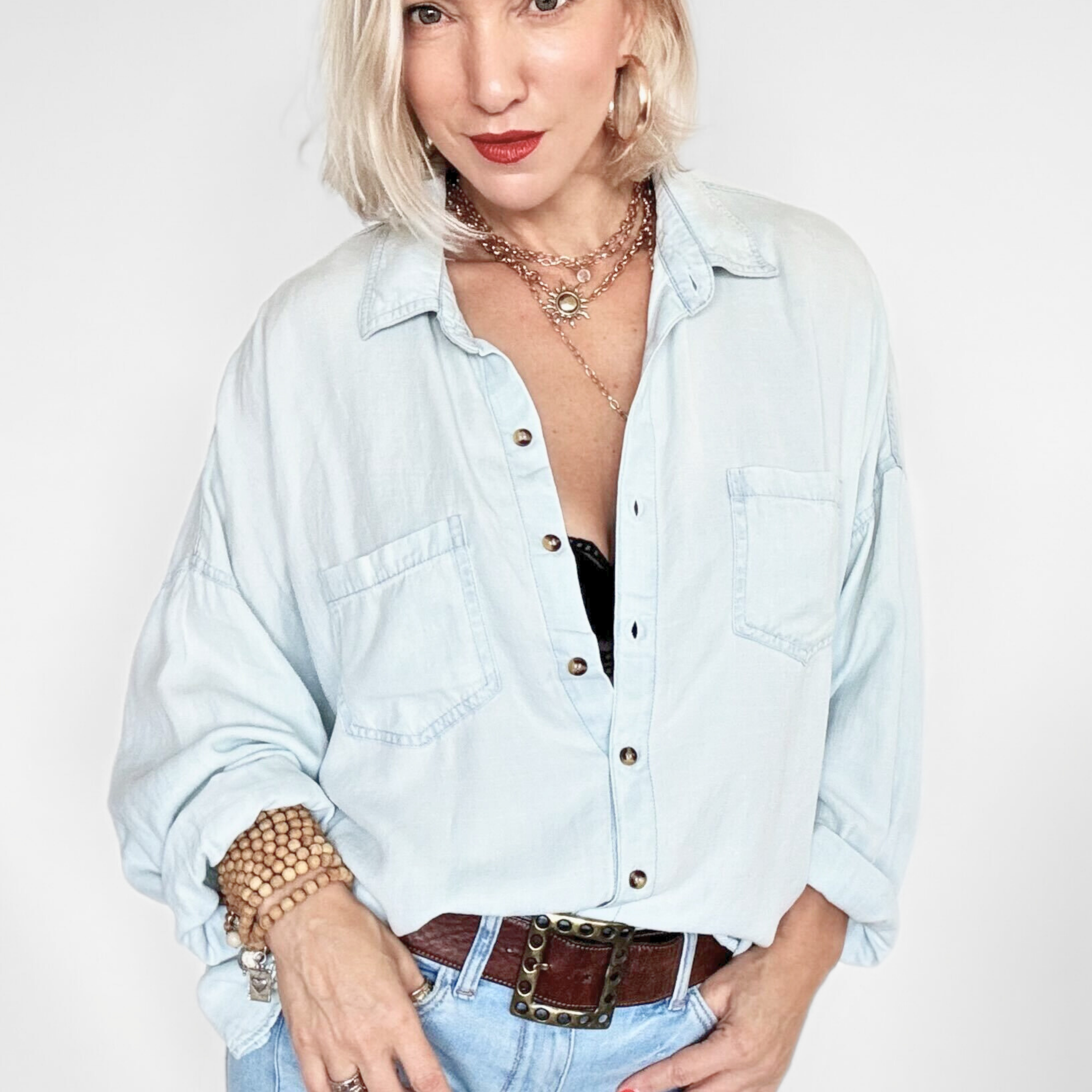 Woman wearing a light wash denim shirt and jeans on a white background