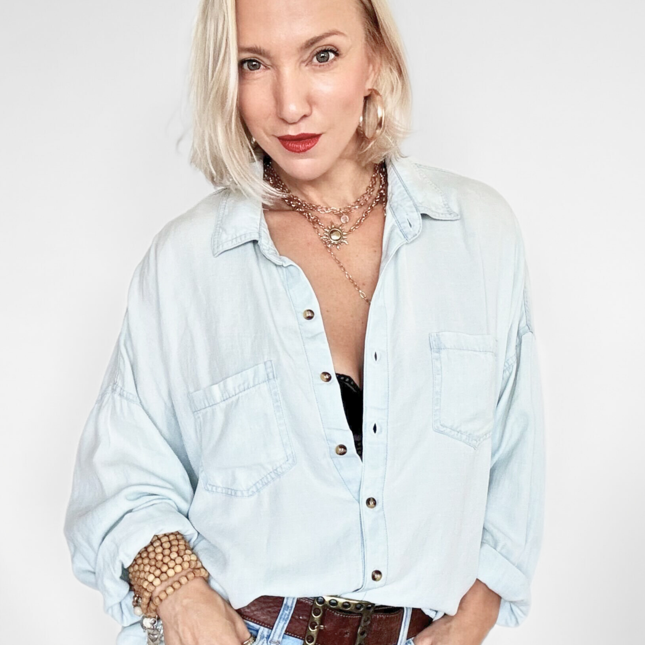 Woman wearing a light wash denim shirt and jeans on a white background