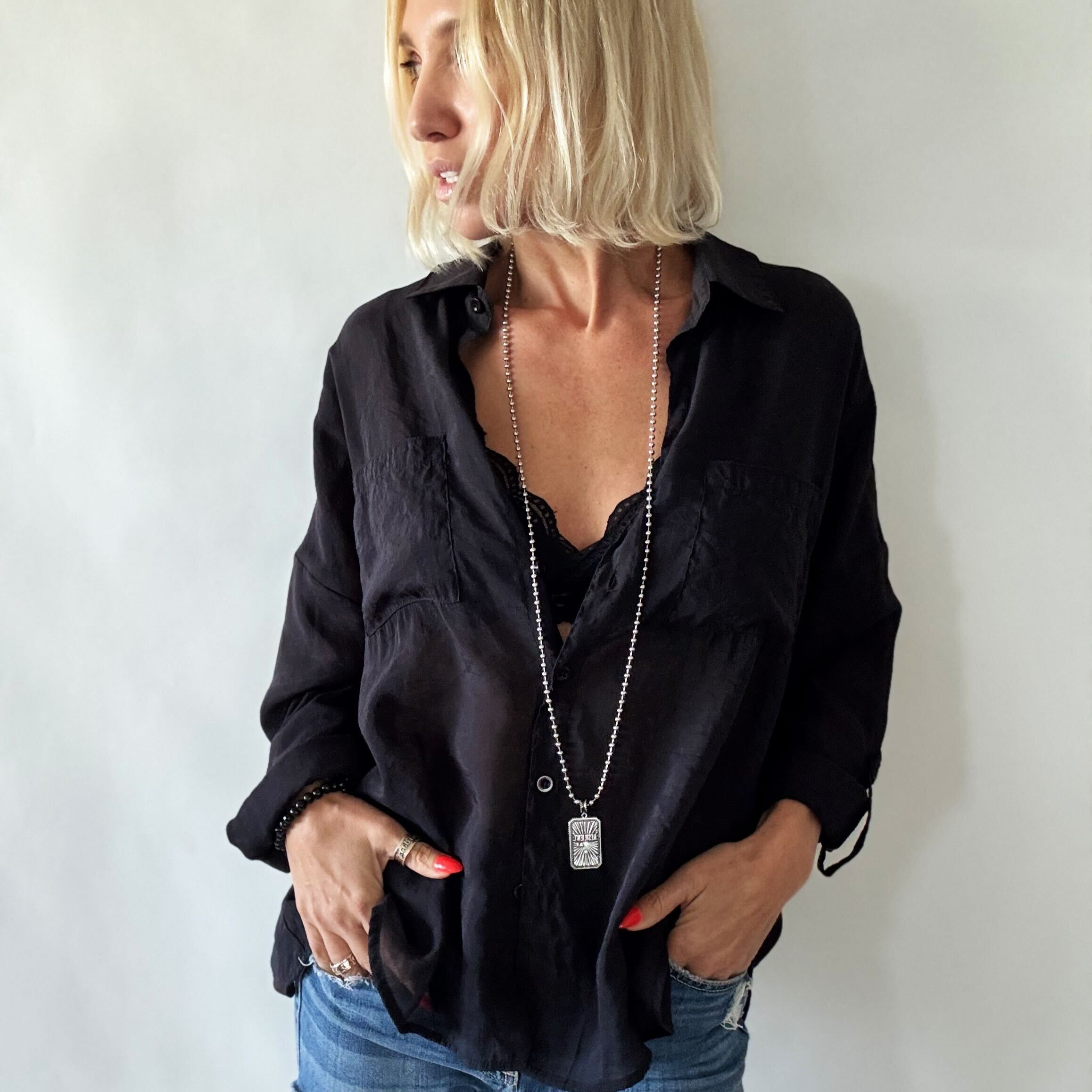 Woman wearing a black shirt and blue jeans with a plain background