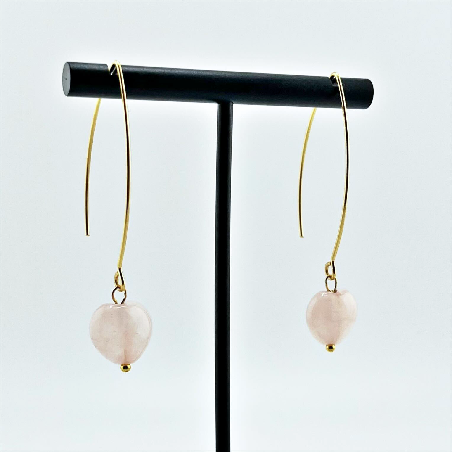 A person wearing small stone drop earrings with a V-shape wire design in a colorless setting.