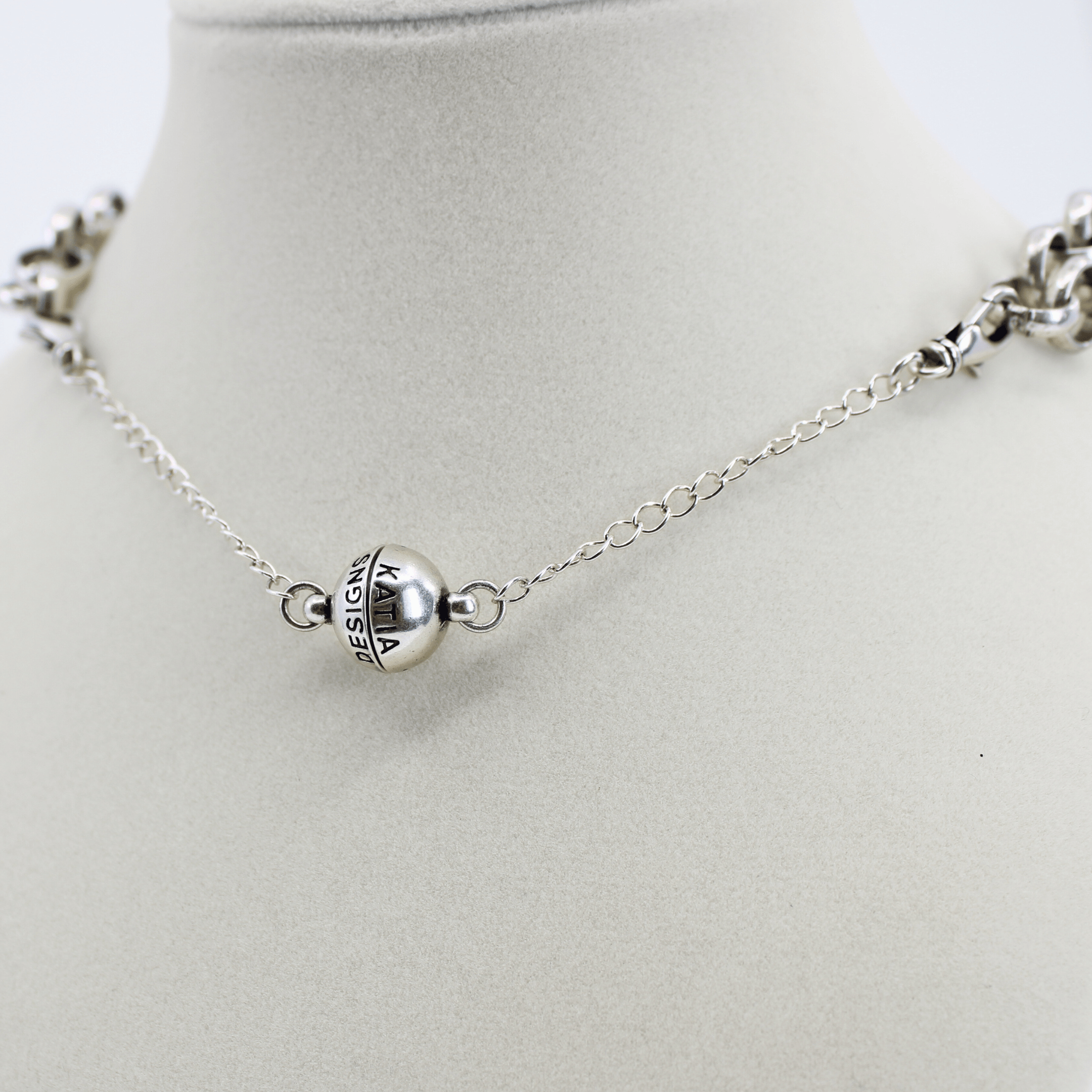 Silver necklace with a round pendant on a mannequin neck against a white background