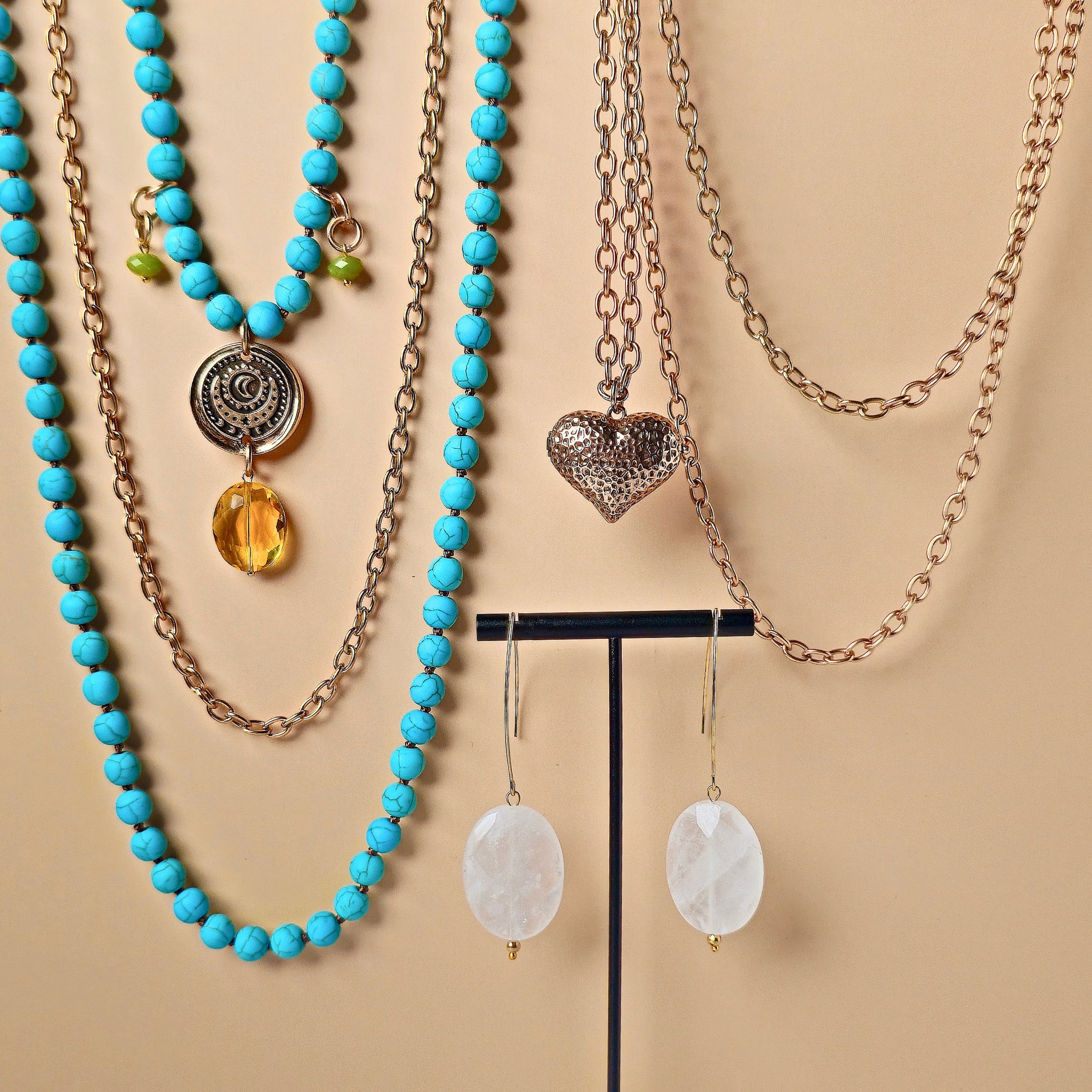 Jewelry set with turquoise beaded necklaces and heart pendant on a beige background