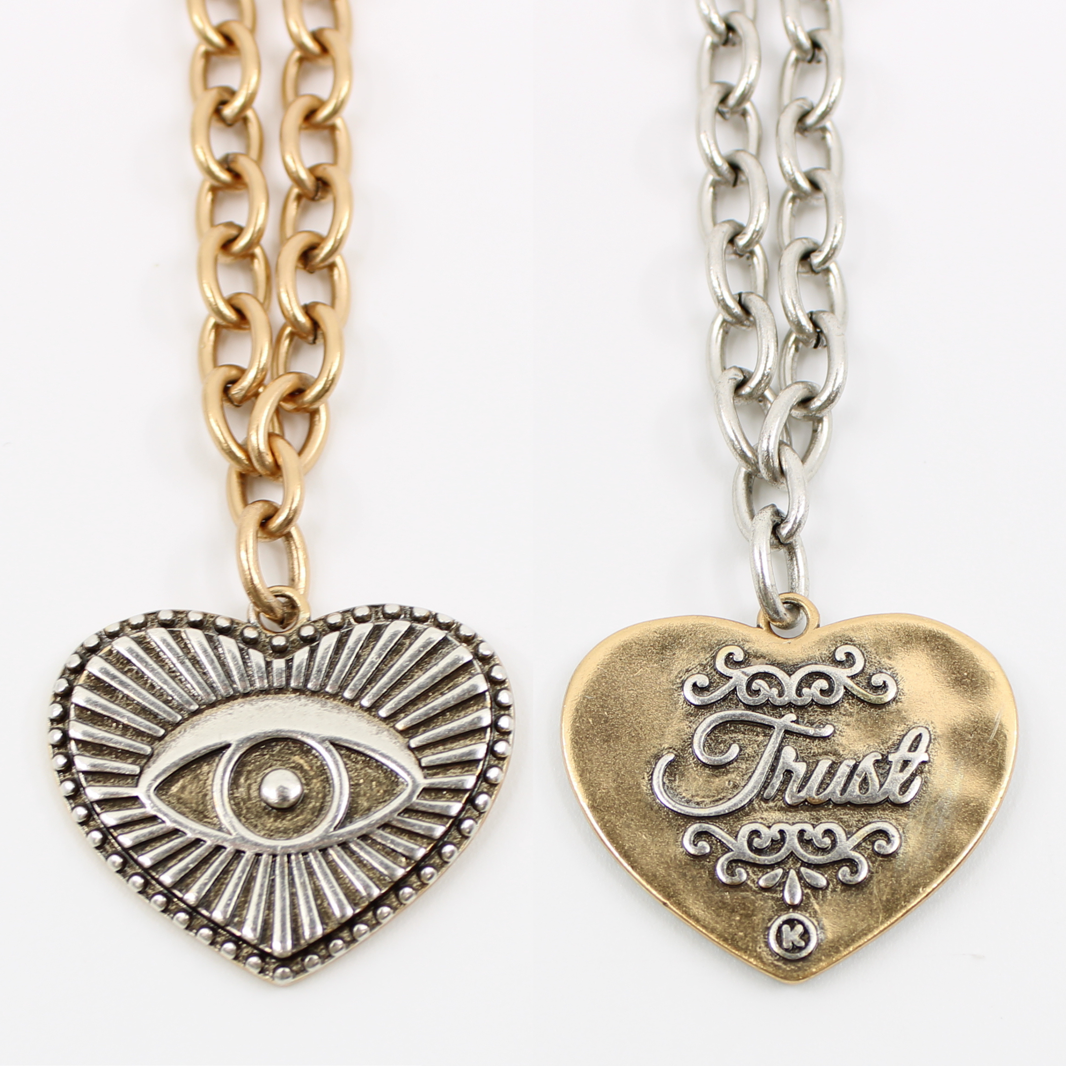 chain choker with a heart-shaped eye pendant, bar clasp, and crescent moon charm. Its mixed metal design adds a unique flair, all set against a white background.