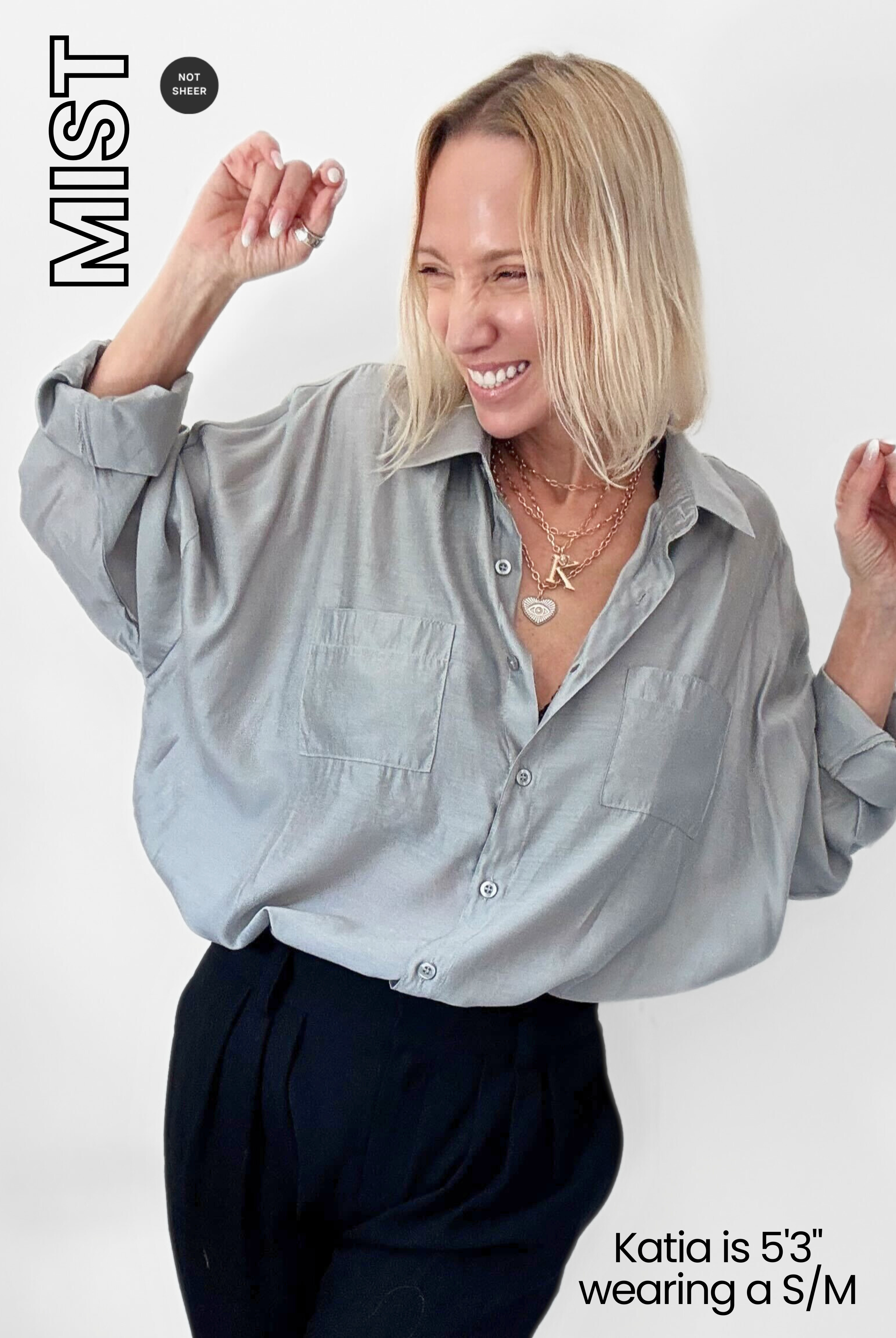 Woman wearing a light gray shirt and dark pants on a white background with 'MIST' branding.