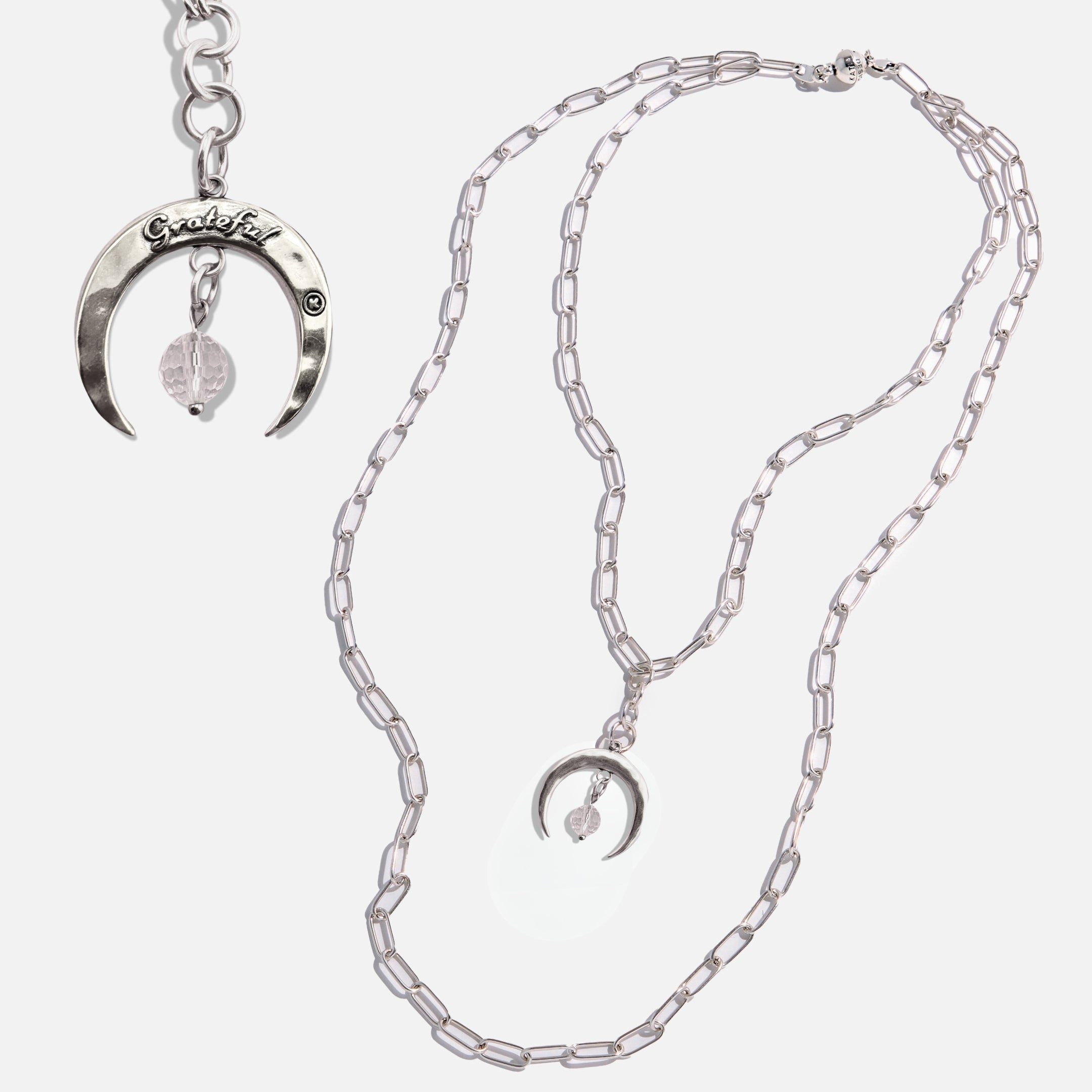 Silver necklace with crescent moon pendant on a white background