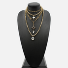 Gold chain necklace with various pendants on a black mannequin bust.