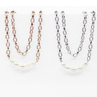 Two layering chain necklaces with pearl accent stones, one plated in gold and the other in silver, displayed against a white background.
