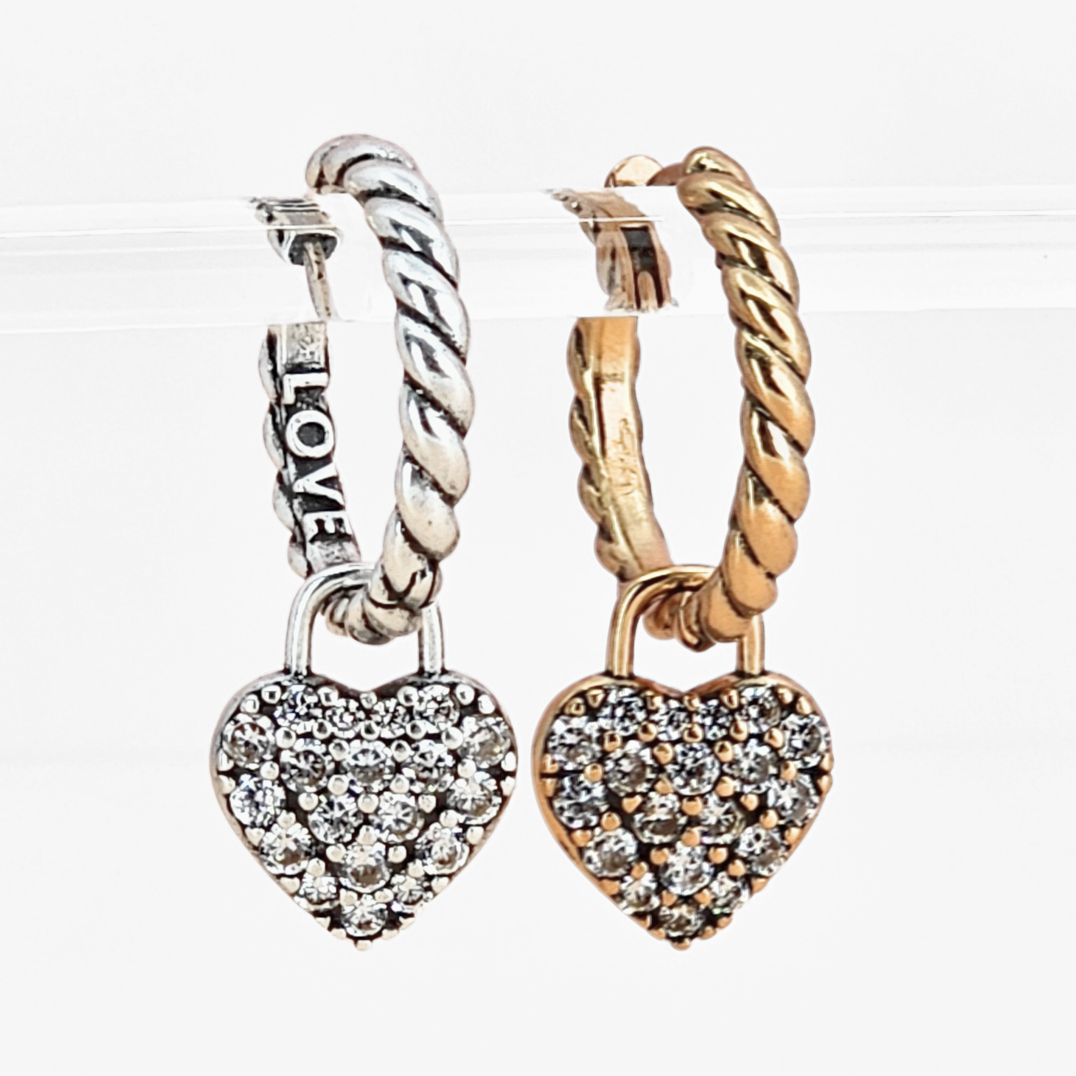 Two heart-shaped hoop earrings, one silver and one gold, on a white background.