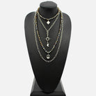 Necklace with multiple chains and pendants on a black mannequin bust.
