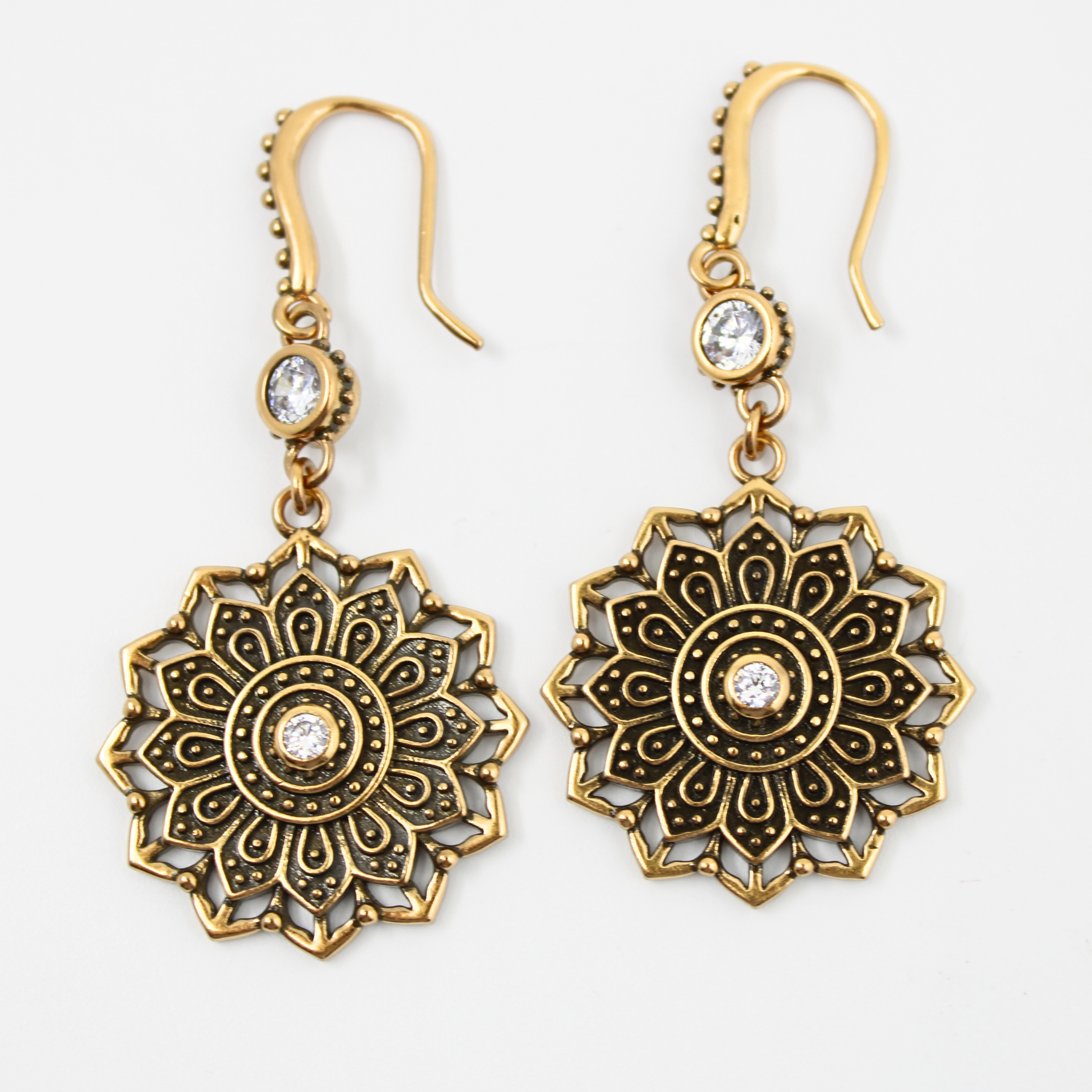 Pair of gold and bronze mandala-style earrings on a white background