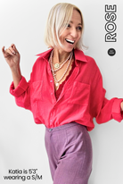 Woman wearing a red shirt and purple pants with 'ROSE' branding.