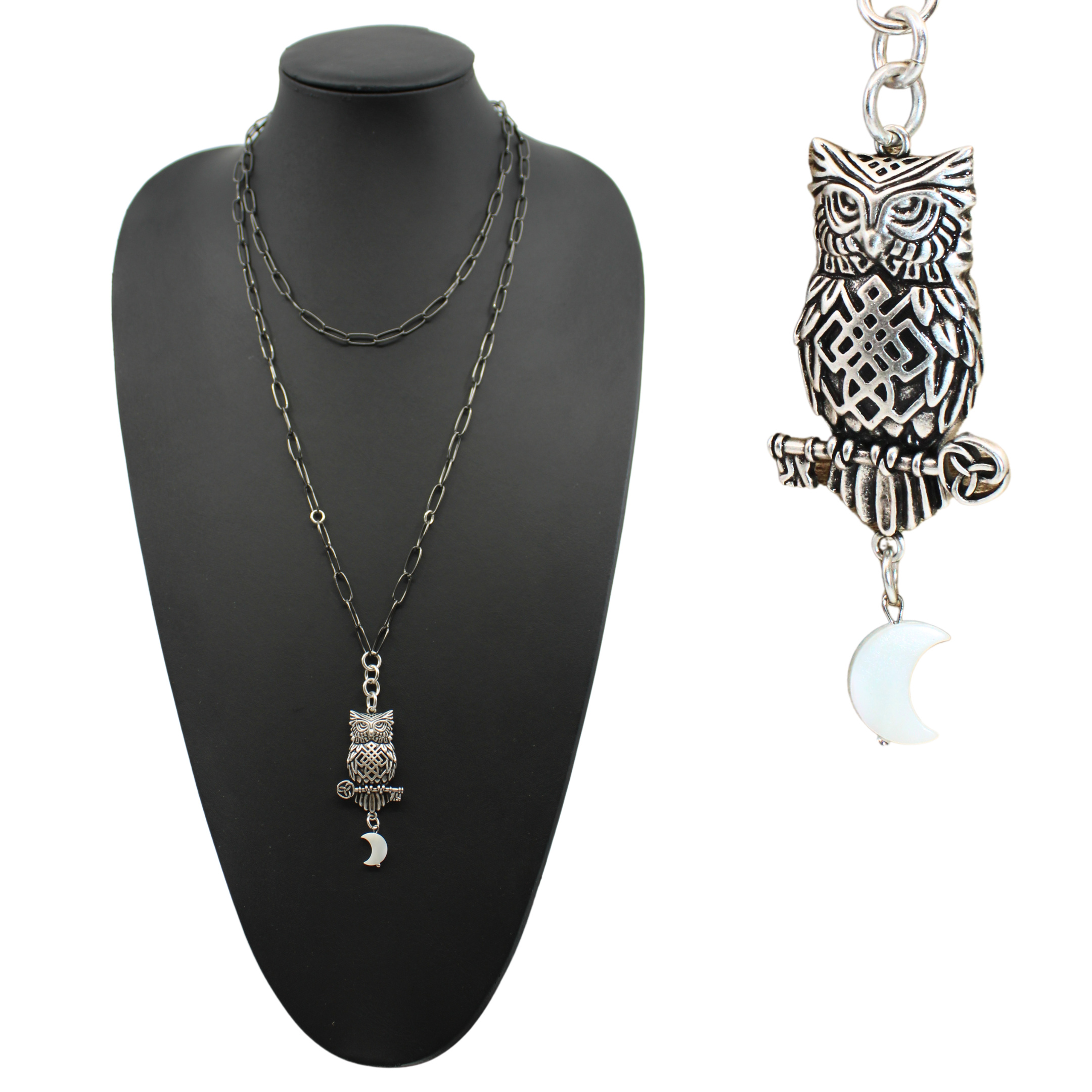 A person wearing a black shirt with lace details, showcasing a gunmetal finish plated brass paperclip chain necklace with an owl pendant and a pearl moon accent.