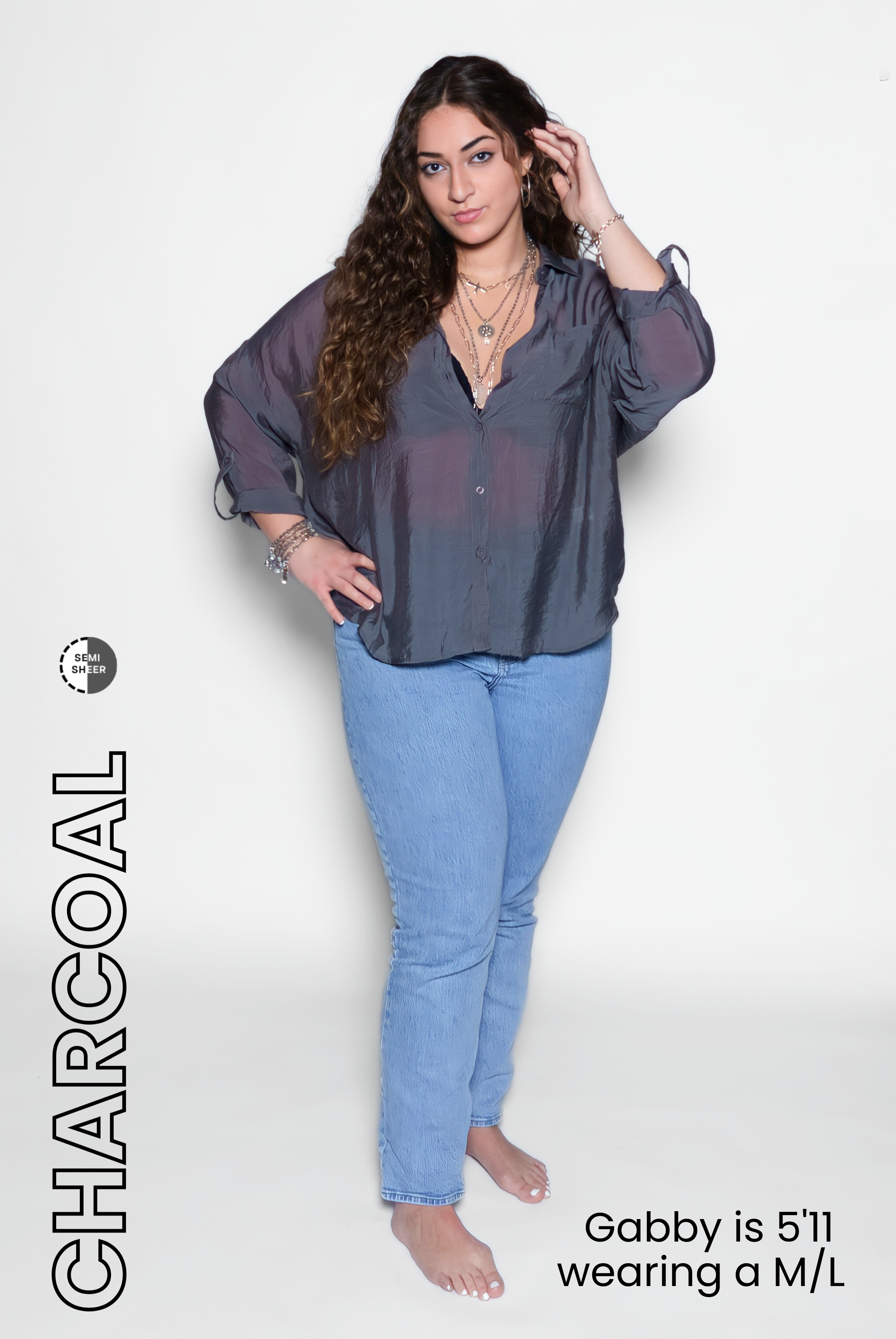 Woman wearing a charcoal gray blouse and blue jeans on a white background