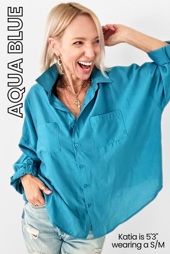 Woman smiling in oversized aqua blue shirt and ripped jeans, exuding a Boho-Chic vibe. Text: Aqua Blue, featuring the versatile Goddess Shirt style. Katia is 53 wearing a S/M.