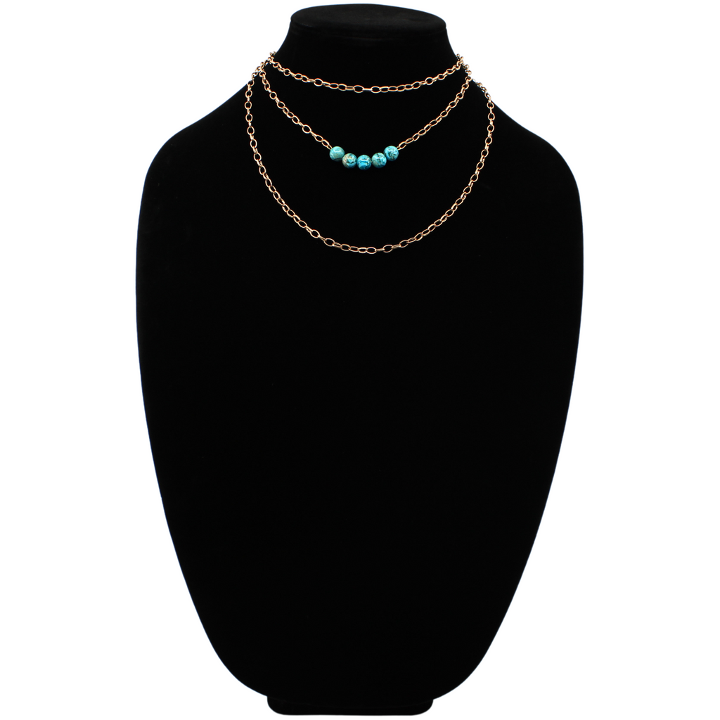 Stainless steel necklace featuring a gold chain with a row of five Aqua Terra Jasper beads, beautifully marbled in blue, set against a black velvet bust. Perfect for layering.