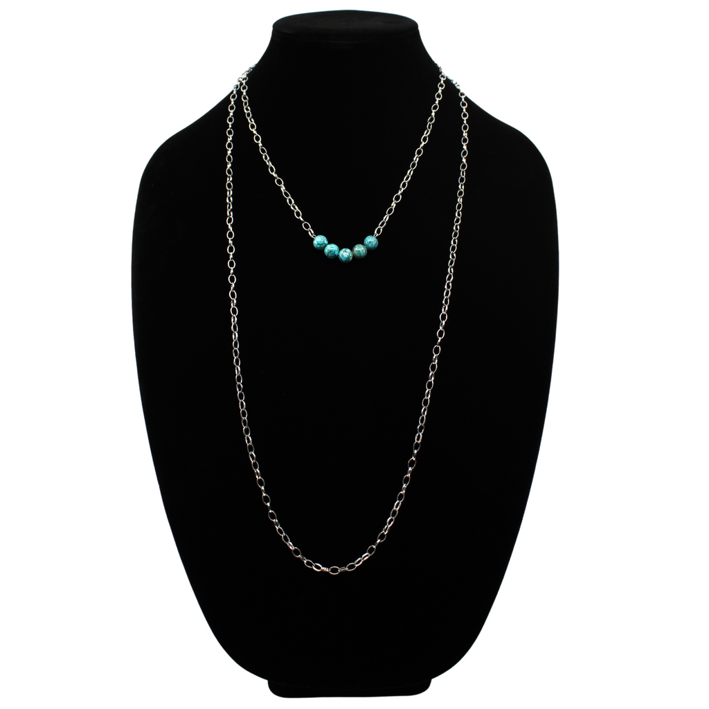 Stainless steel necklace featuring a silver chain with a row of five Aqua Terra Jasper beads, beautifully marbled in blue, set against a black velvet bust. Perfect for layering.