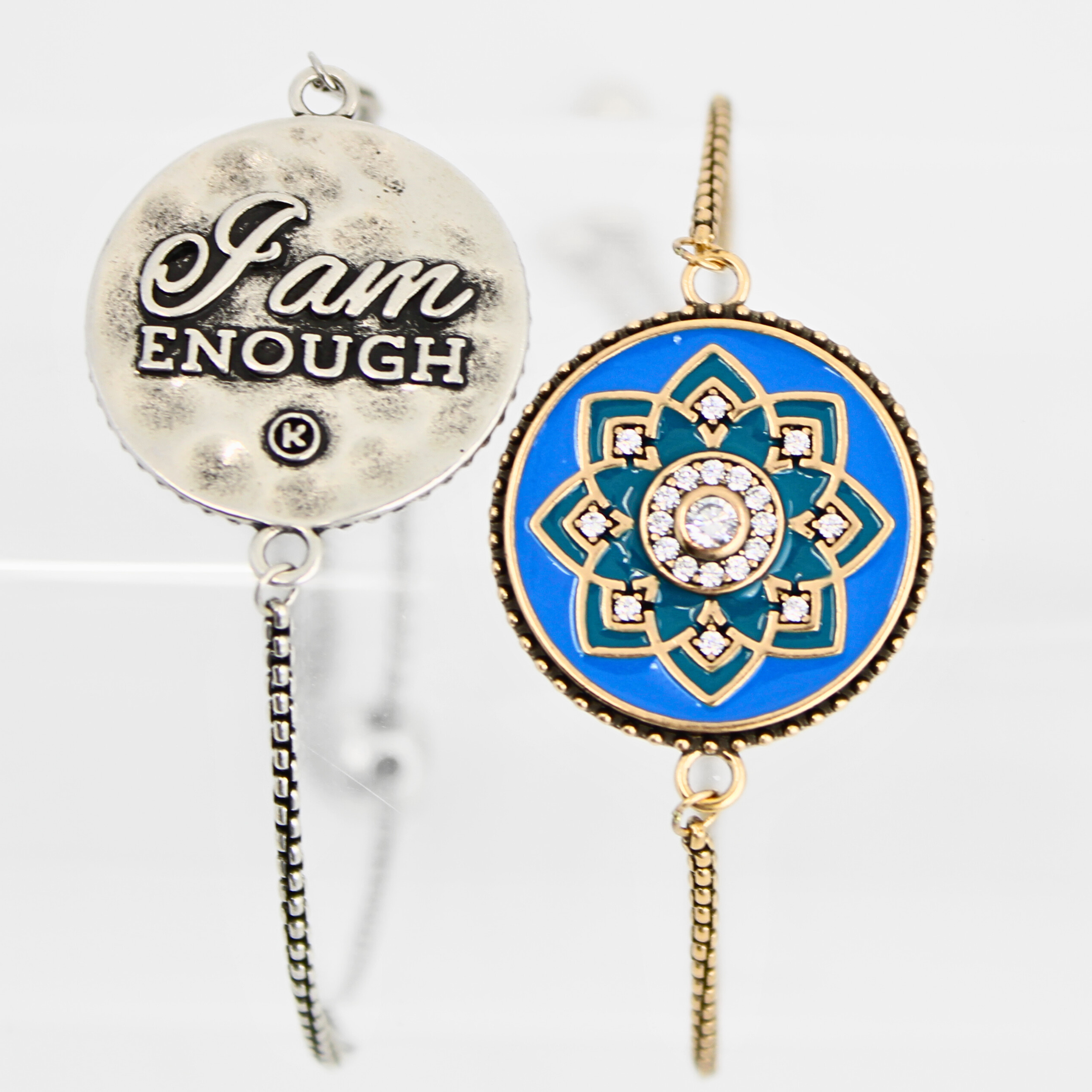 Two necklaces on a white background, one with 'I am Enough' pendant and the other with blue and gold mandala design.