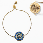 Gold bracelet with blue mandala charm and 'I am enough' pendant on a white background