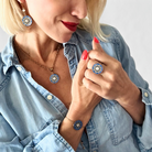 Woman wearing a blue and gold necklace, ring, and earring set.