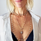 Woman wearing a layered necklace with a star pendant on a plain background