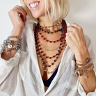 Woman wearing multiple necklaces and bracelets with a white background