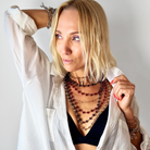 Woman wearing multiple necklaces and a white shirt against a plain background