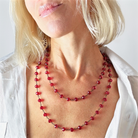 Close-up of a person wearing a red beaded necklace against a plain background