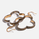 A pair of composite drop earrings with French ear wire, featuring a mixed metal design and an inscription inside the clover shape.